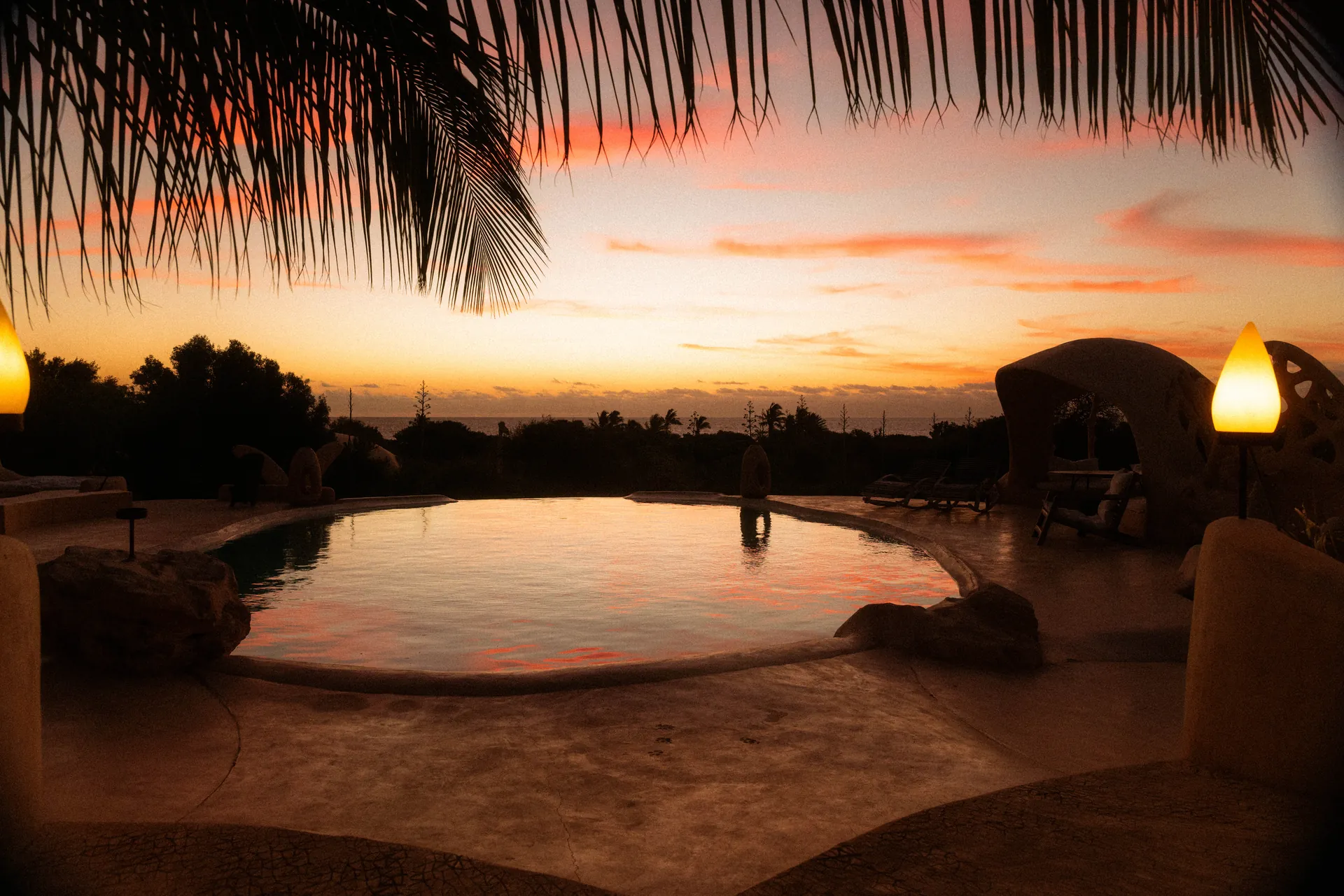 A lodge swimming pool under palm fronds at sunset, Madagascar