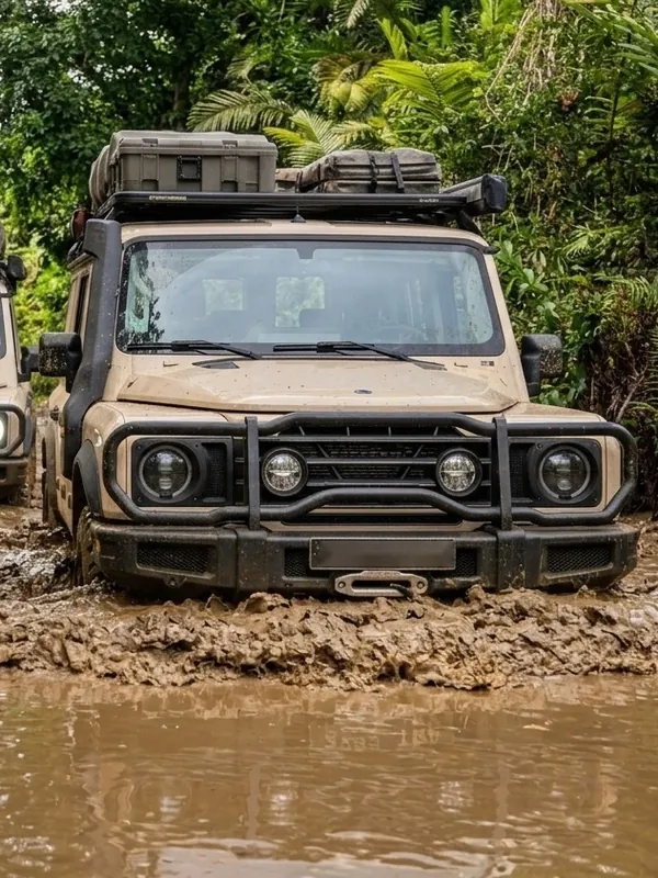 An Ineos Grenadier driving through a muddy rainforest track in Madagascar