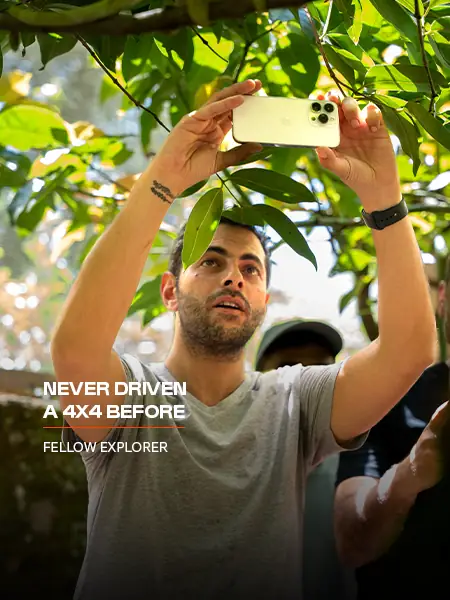 A fellow explorer taking a photo under the trees on a Nomadic Road expedition: Never driven a 4x4 before