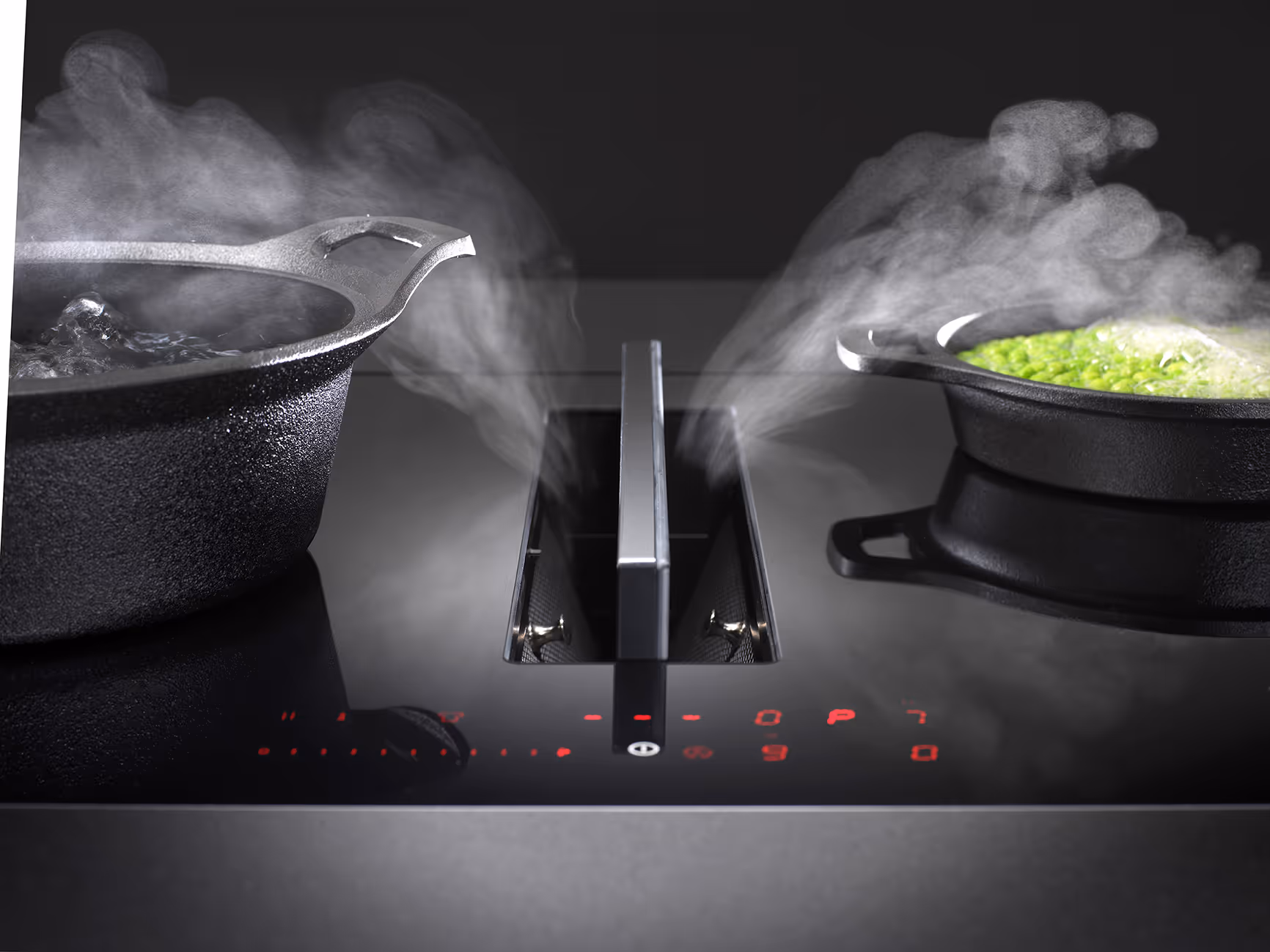 Close-up of a modern stovetop with built-in ventilation, showing two cast iron pots emitting steam while cooking. The control panel with red LED lights is visible in the foreground.