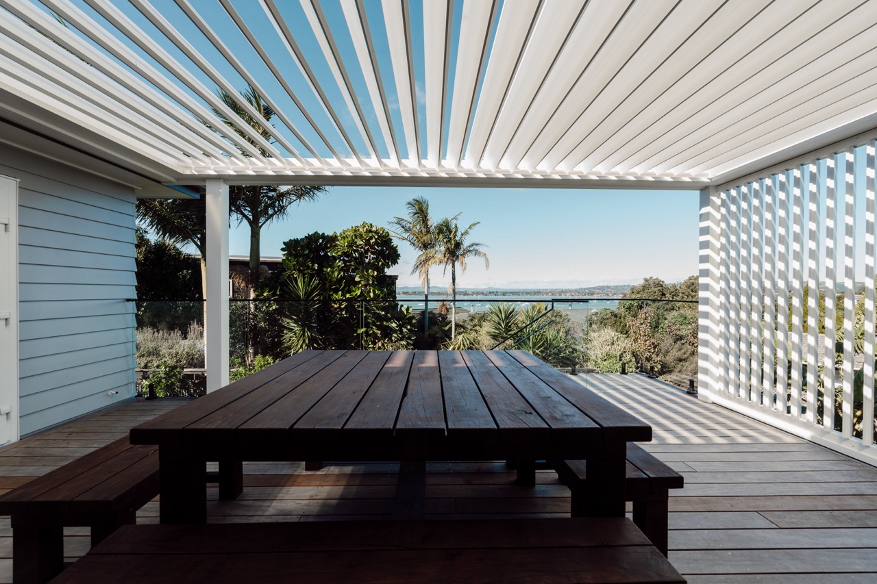 A wooden picnic table sitting under a pergolated roof