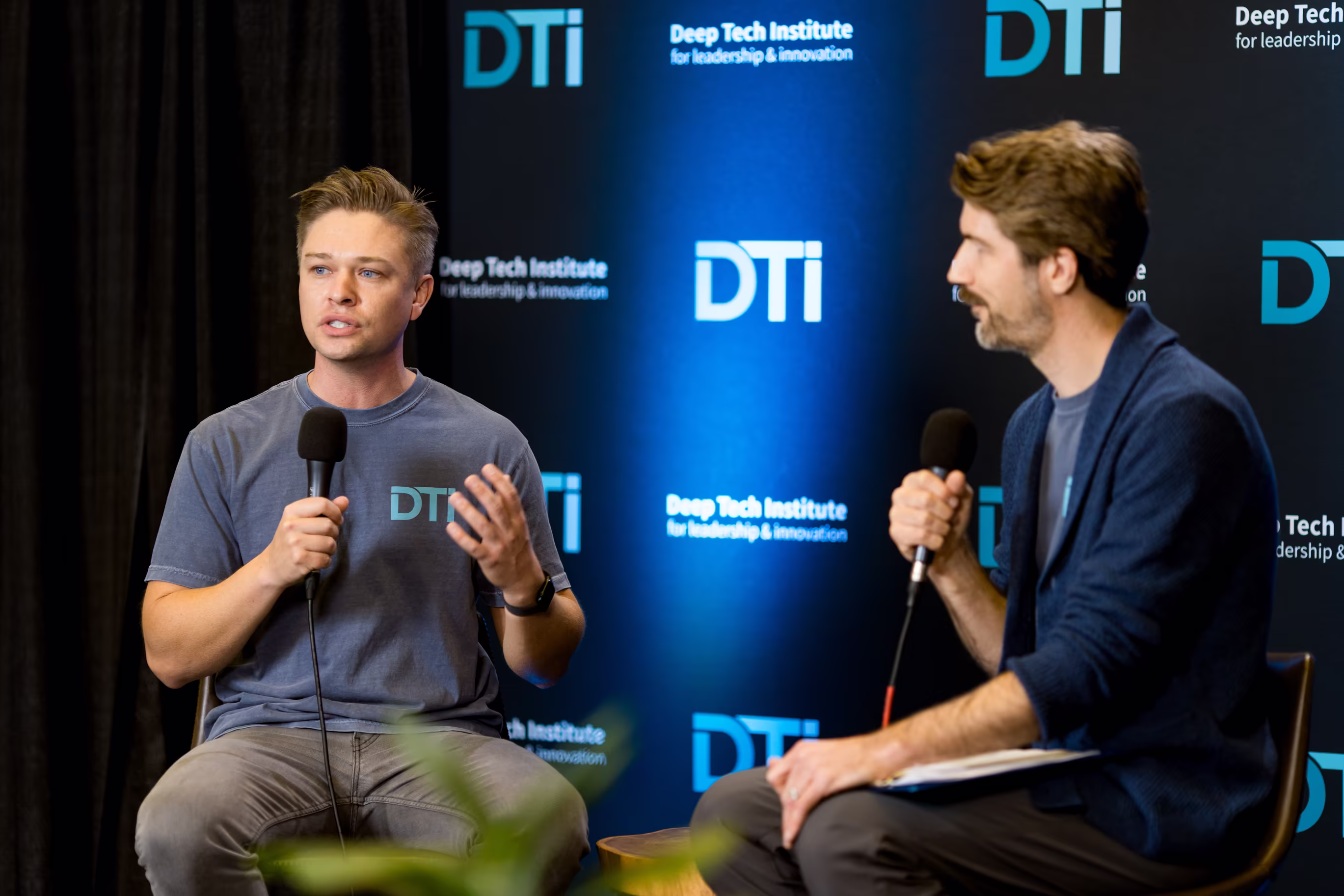 Dew Myers and Ryan Haggerty of Deep Tech Institute talking in a panel on stage at Robotics and AI Discovery Day 2025