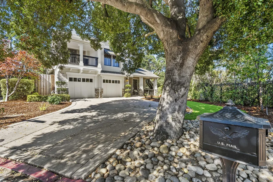 A two-story white family home with mature trees and a large lawn in Palo Alto, California