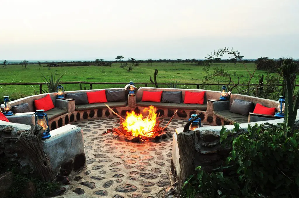 A glowing fireplace surrounded by cozy seats overlooking the Mara savannah at Zebra Plains Mara.