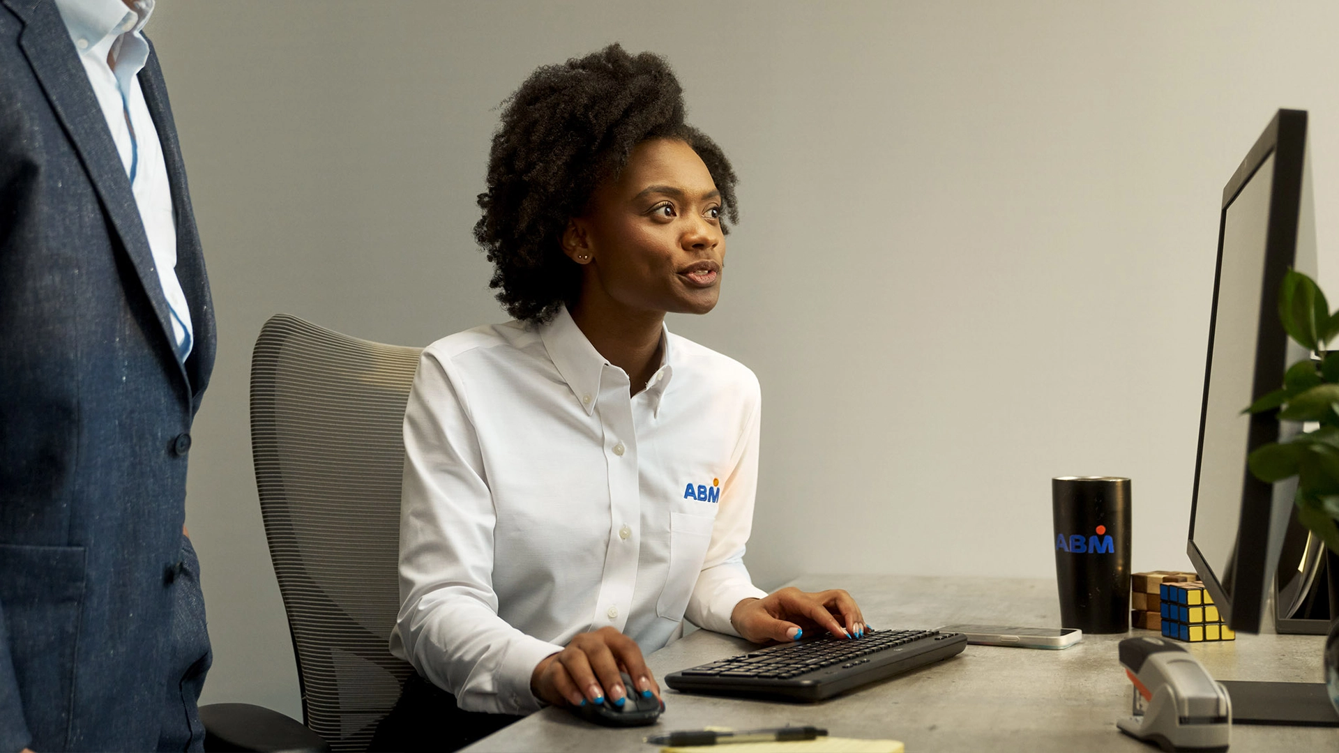 A woman sitting at a desk while using a keyboard and computer mouse