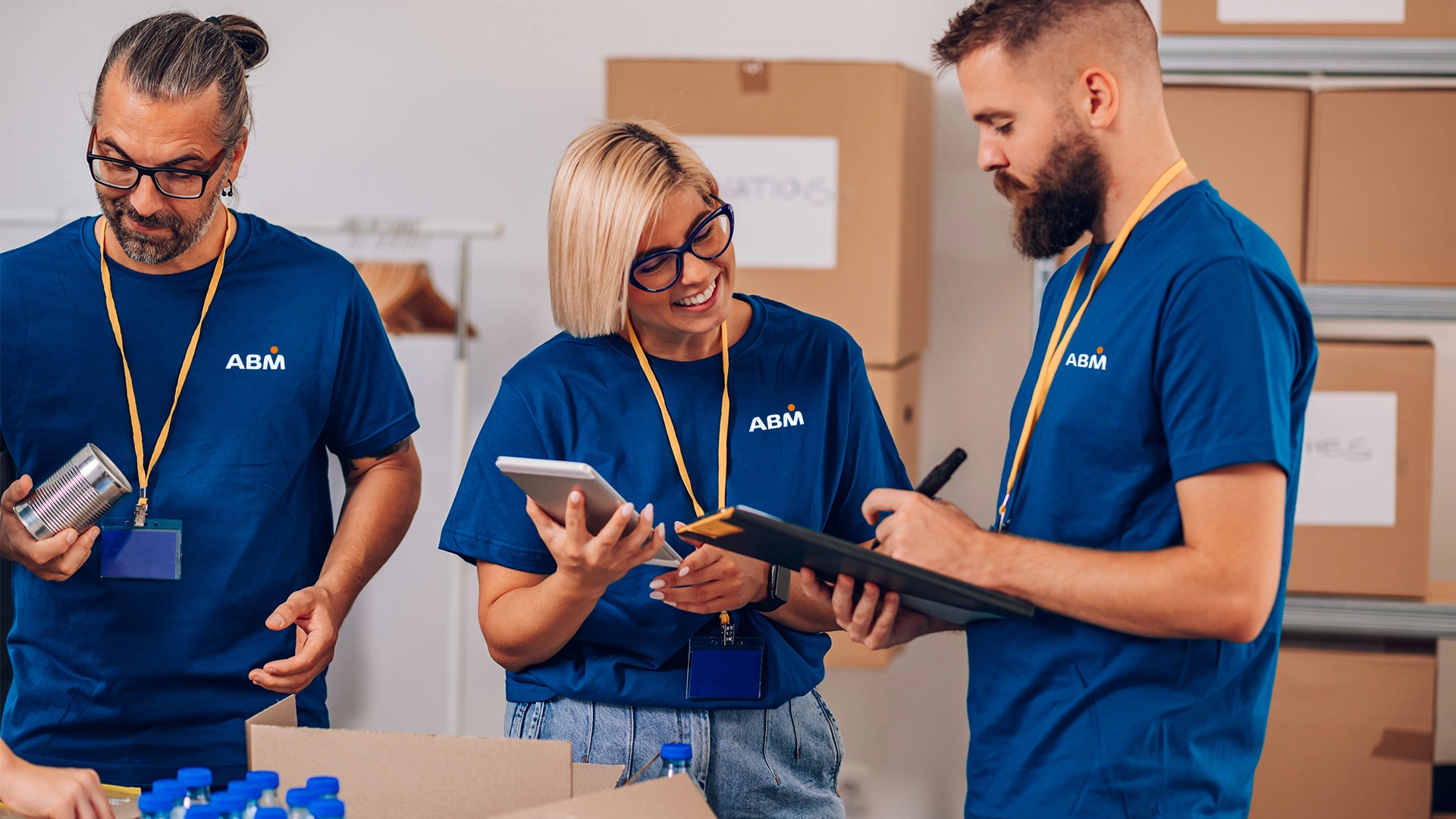 Three people in ABM-branded tee shirts and lanyards interacting