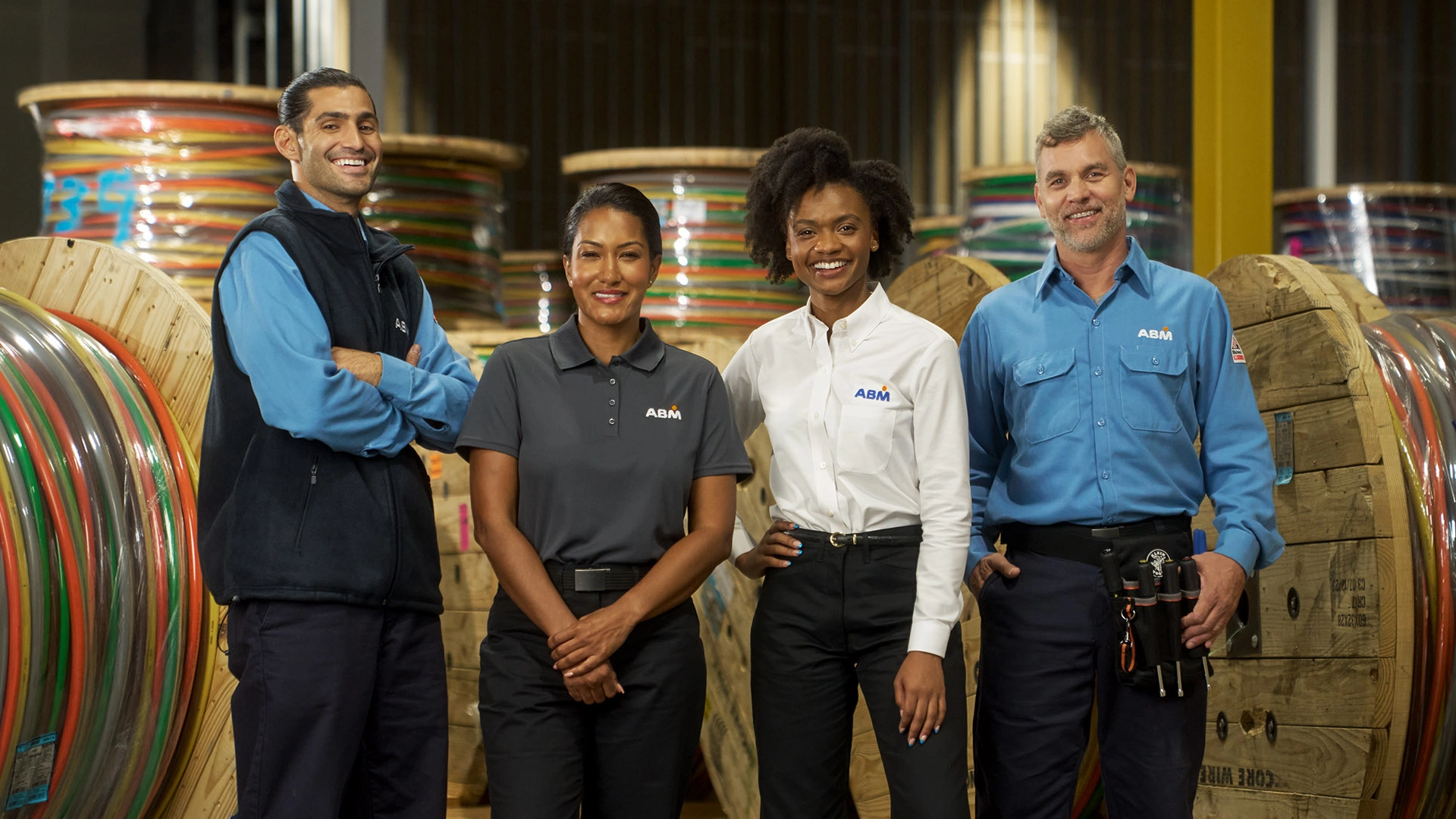 Four people in ABM uniforms standing together in a warehouse