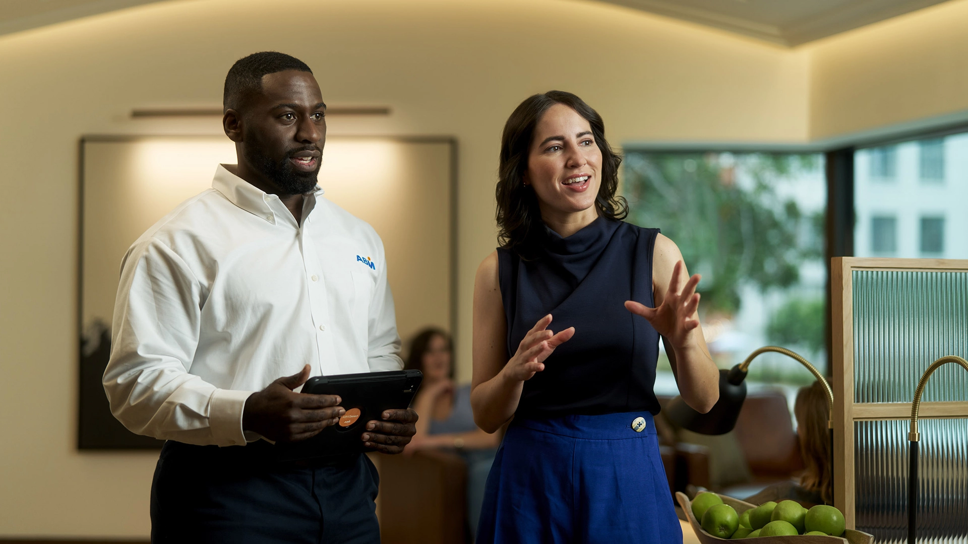 A woman explaining something to a man in an ABM uniform, inside of an office