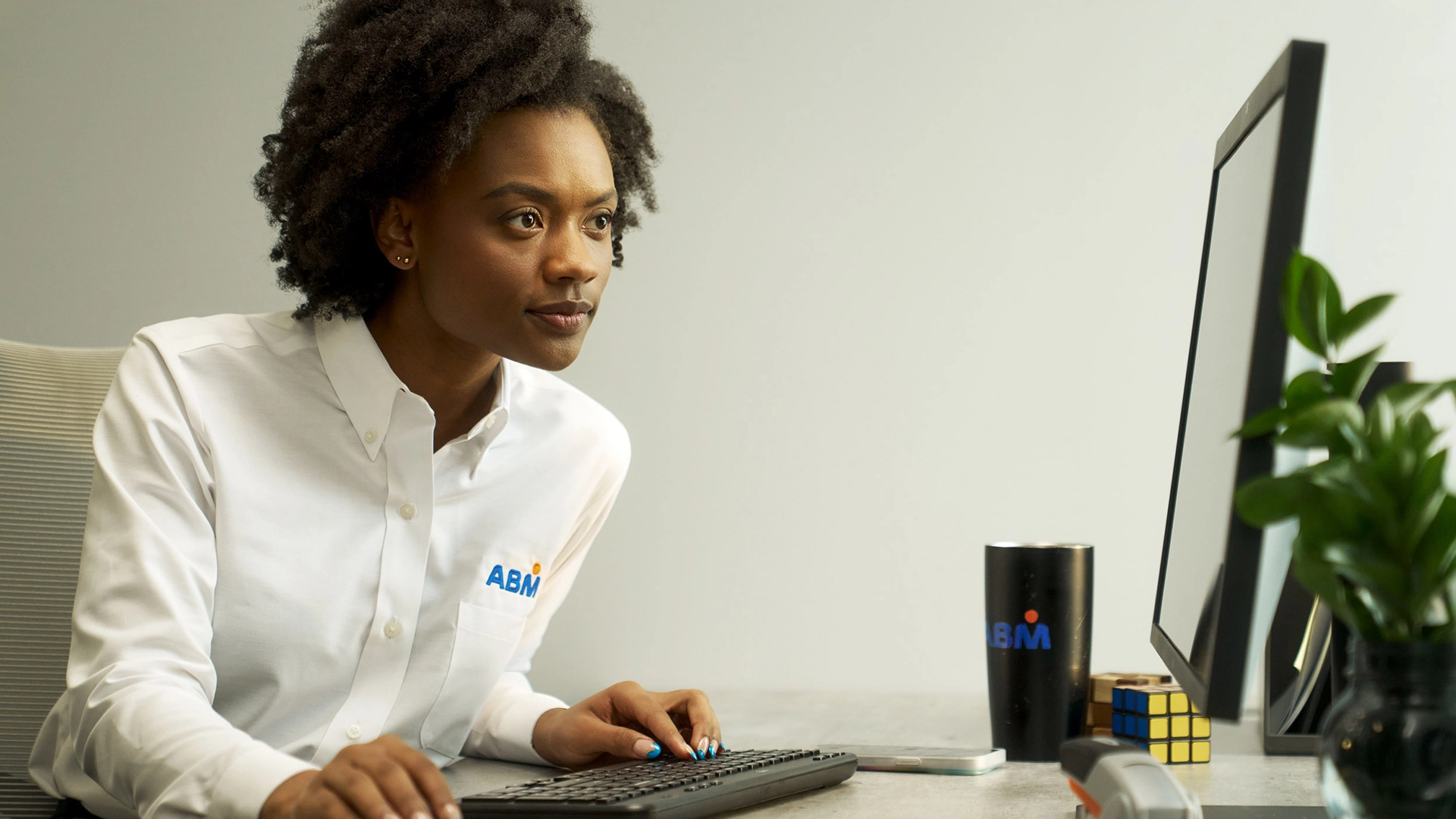 A woman sitting at a desk, leaning in to look at a computer monitor