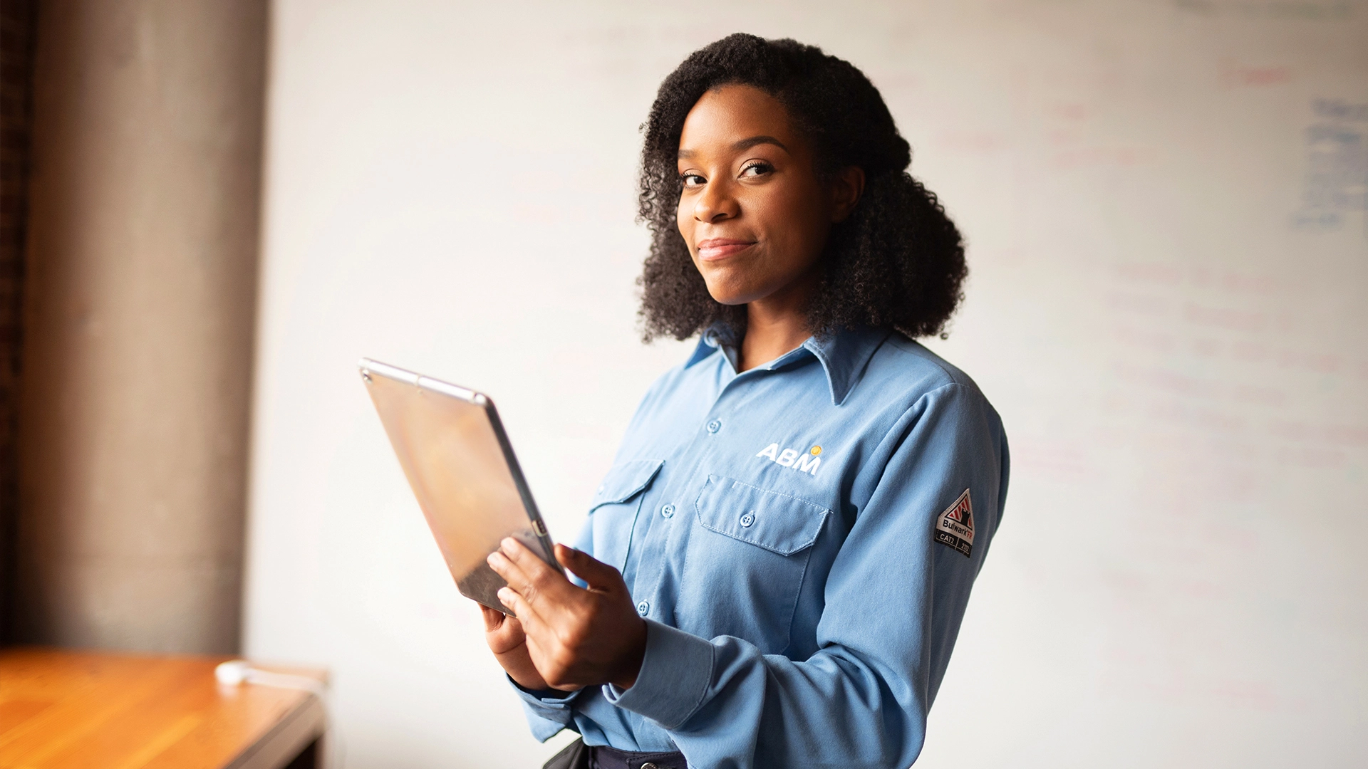 An ABM employee holding a tablet in a workplace setting