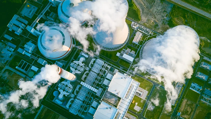 Aerial view of a power generation plant with large cooling towers emitting steam.
