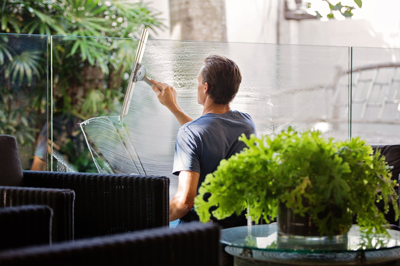 A man is washing a glass office partition.