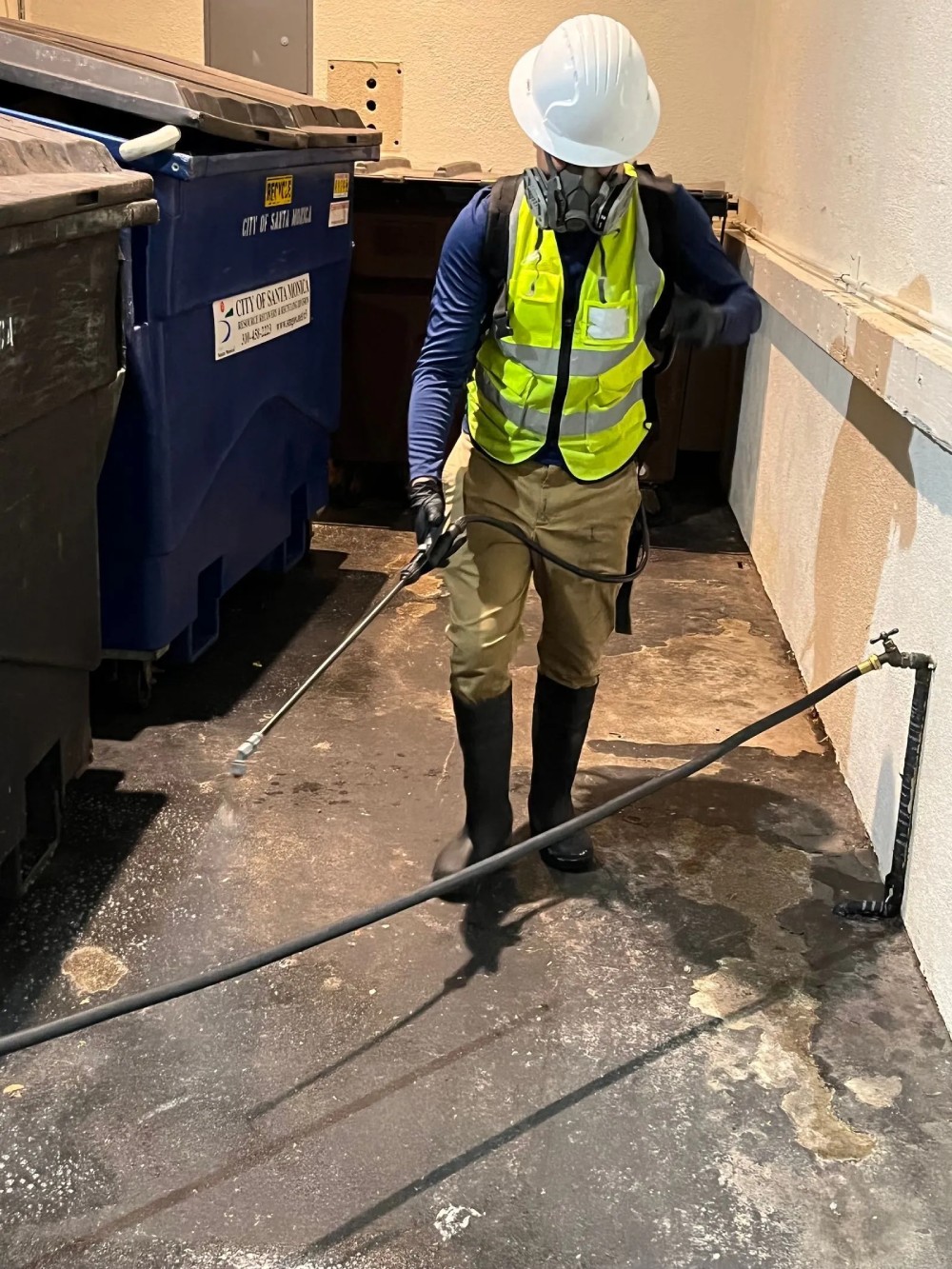 A man is degreasing dumpsters.