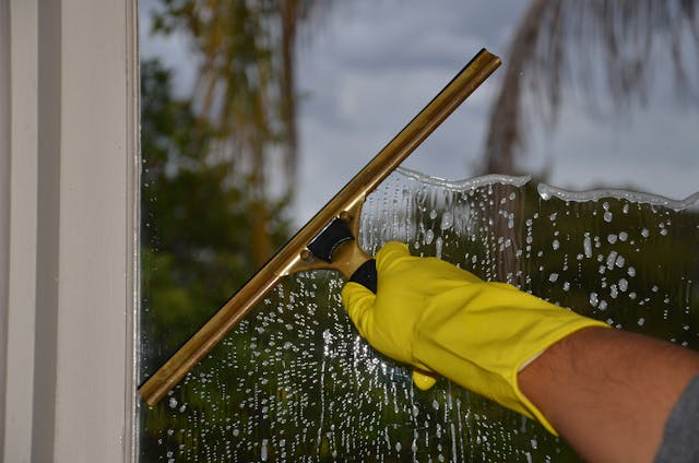A person is cleaning a window with a squeegee.