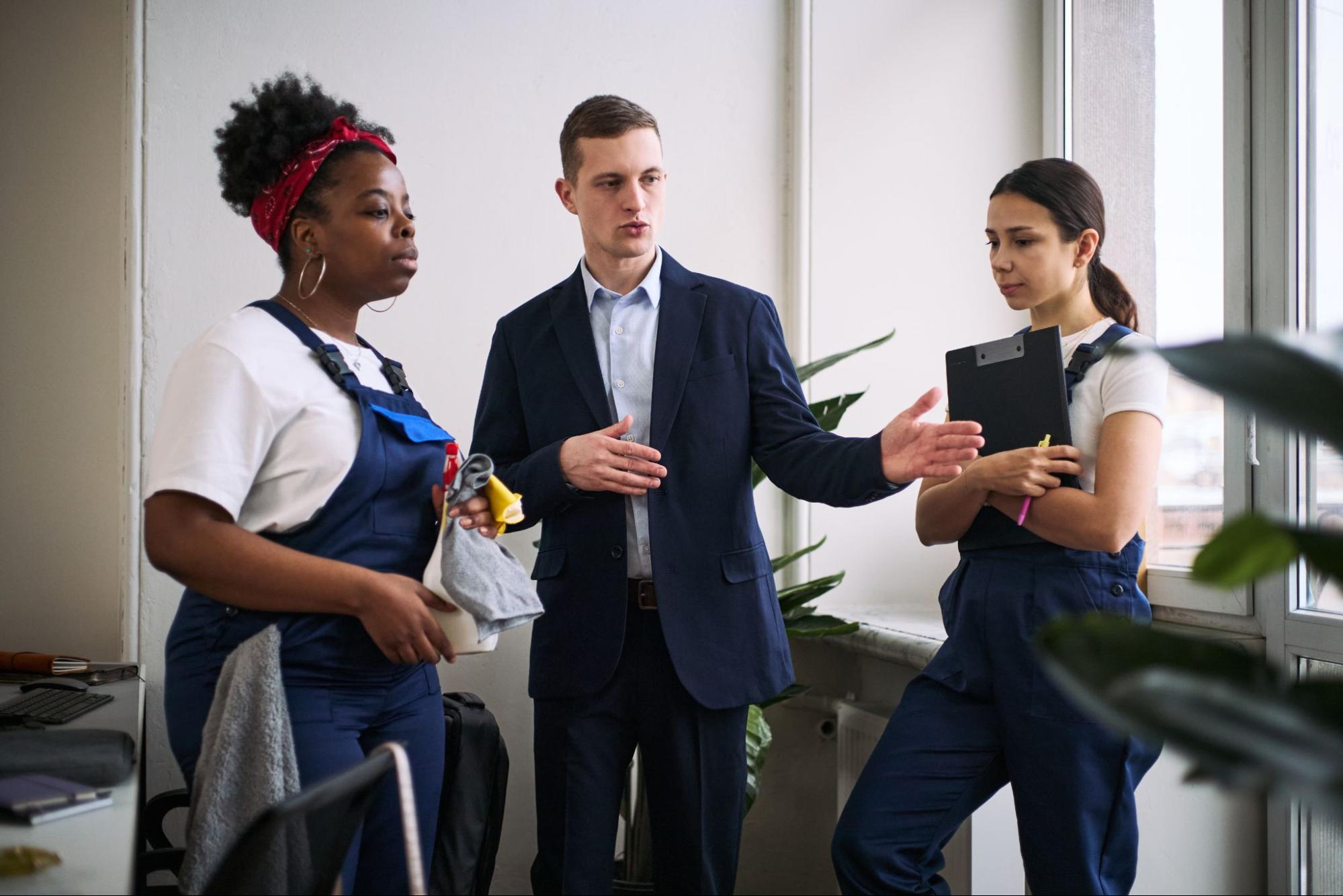 A supervisor directs cleaning staff in an office