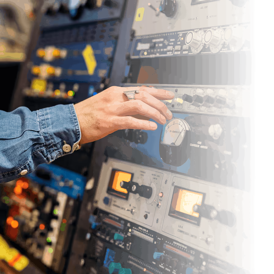 A hand adjusting a knob on professional audio mixing and radio equipment rack.