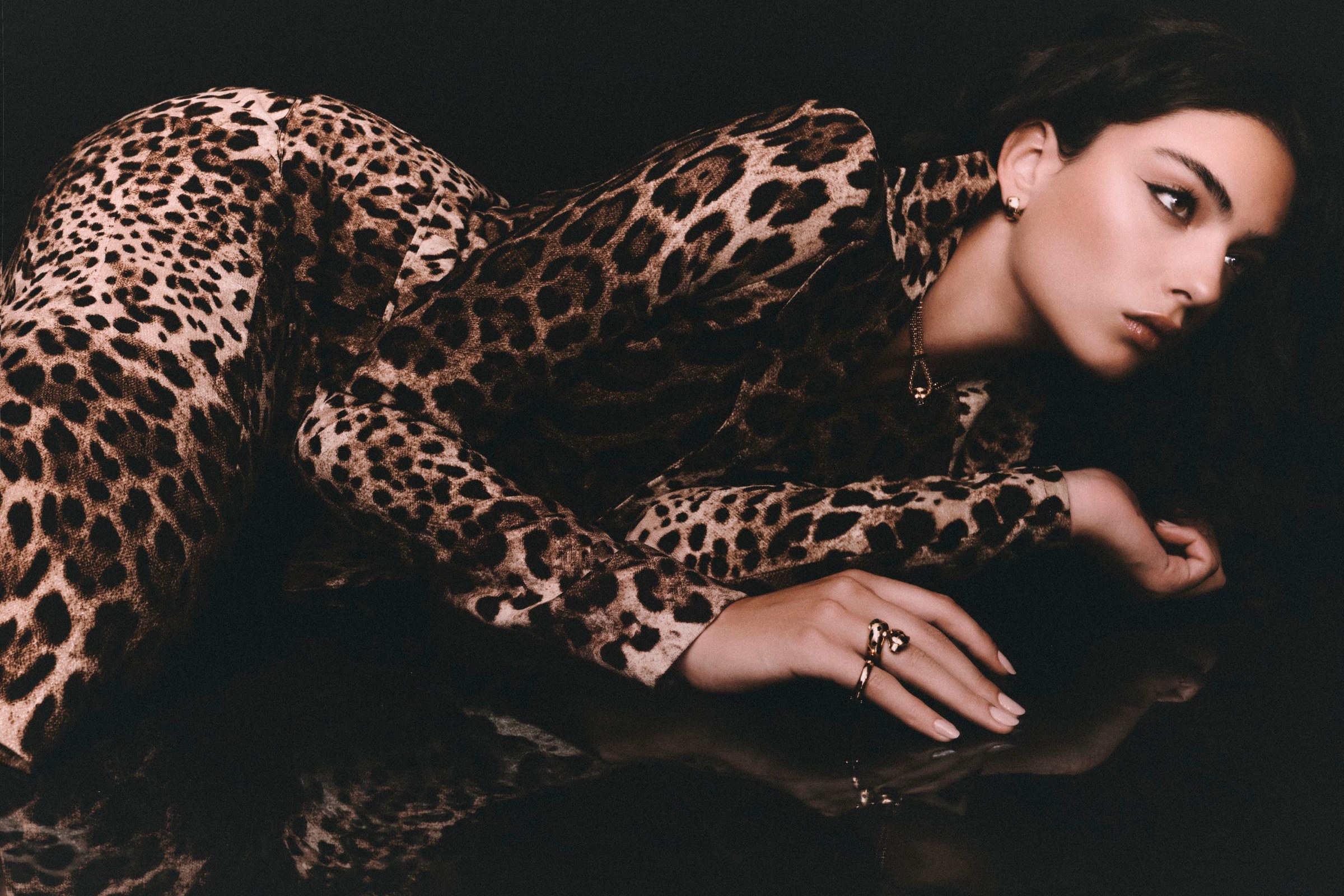 Wide view of Deva Cassel reclining in a leopard-print look with her reflection below.