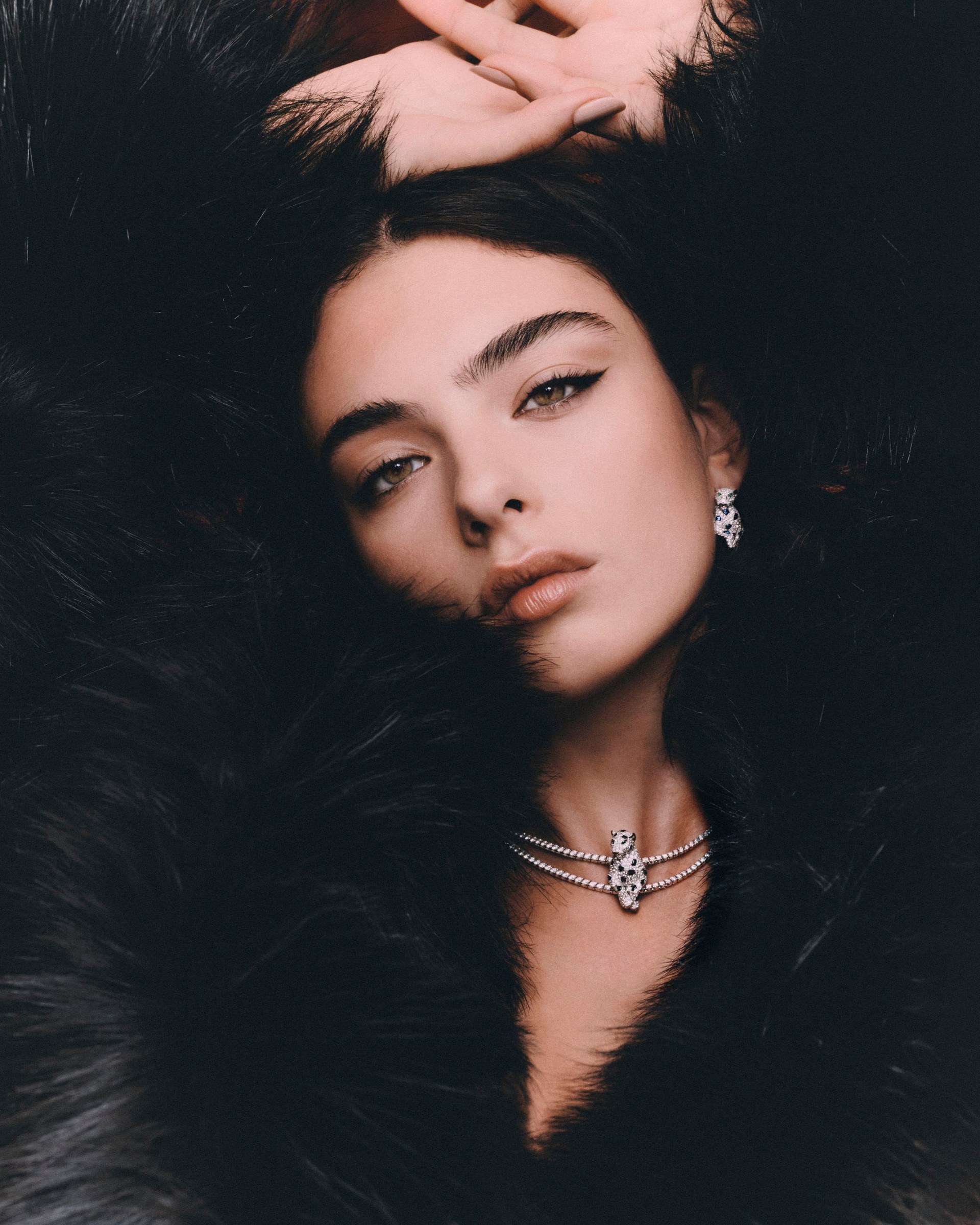 Deva Cassel framed by black feathers, wearing a diamond necklace and earrings.