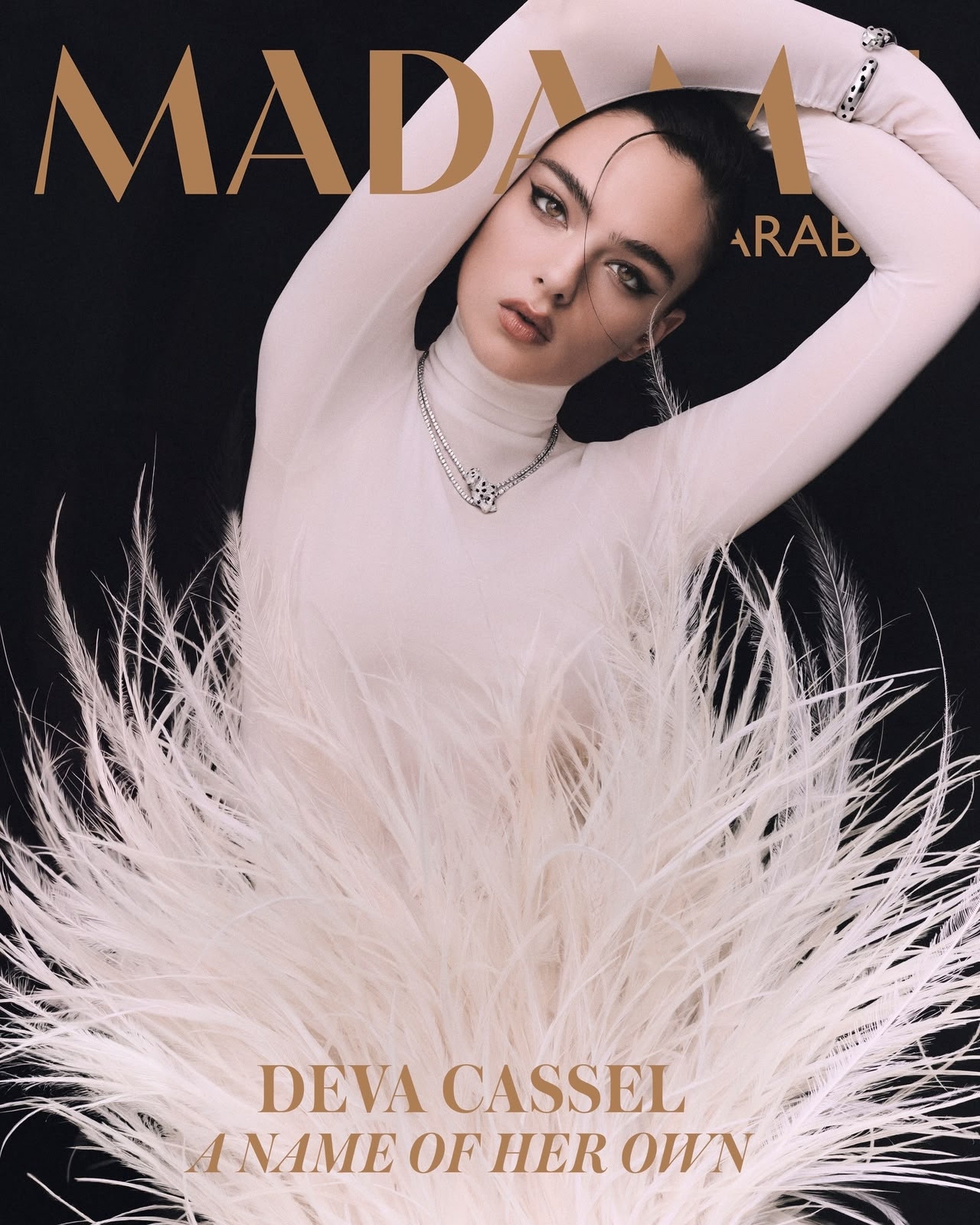 Deva Cassel in a pale look and white feathers on the gold-lettered MADAME Arabia cover, A Name of Her Own.