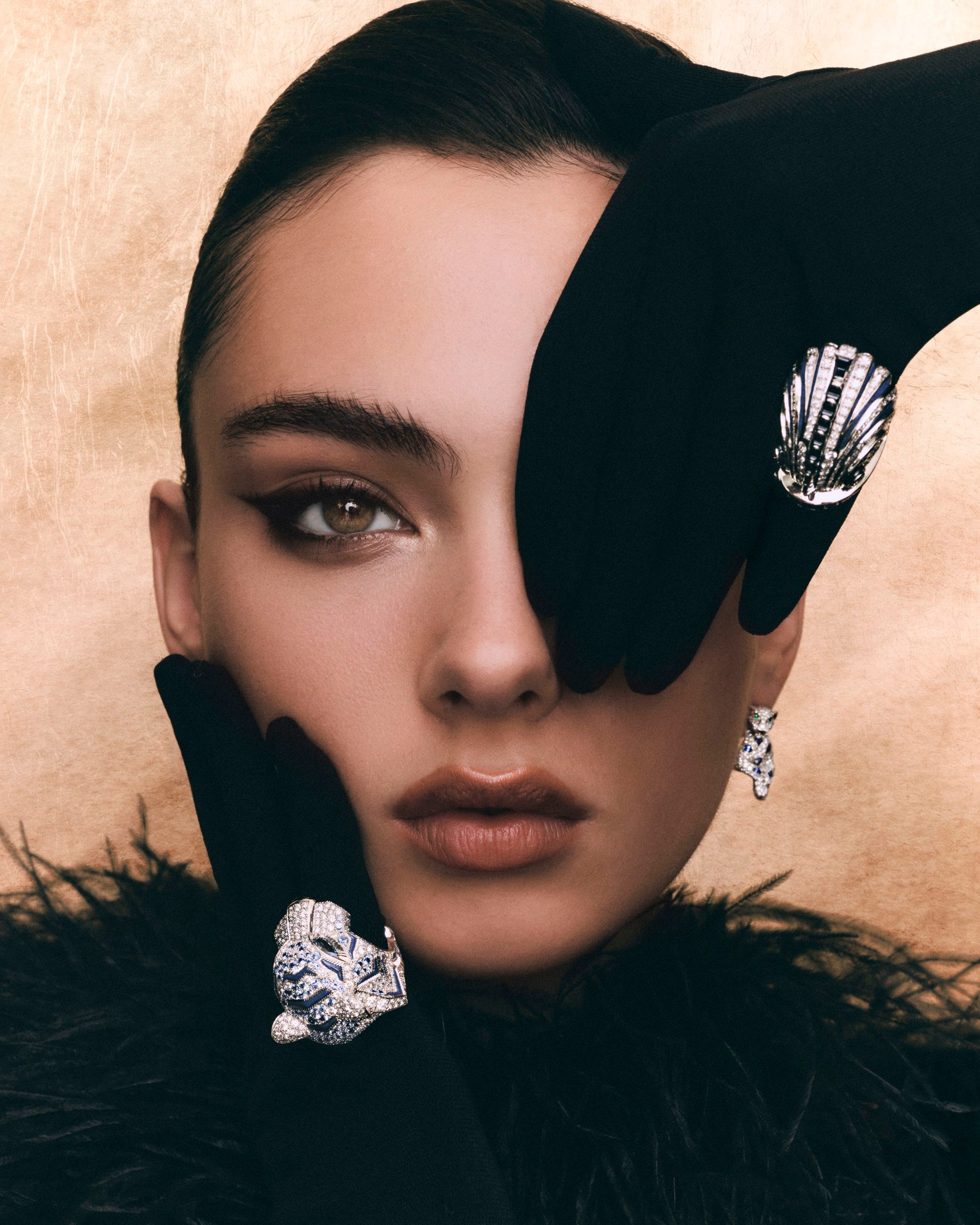 Close portrait of Deva Cassel with a black-gloved hand over one eye and sculptural jewellery.