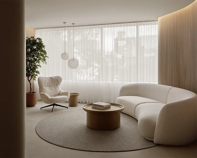 Stylish waiting room with a white curved sofa, a wall made of wooden slats, and spherical pendant lights