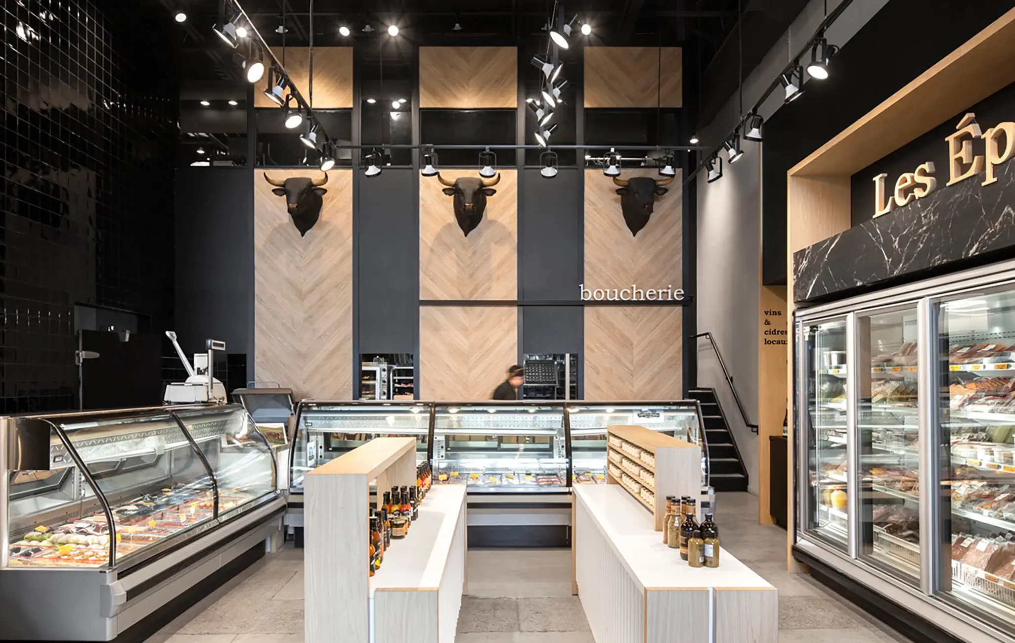 A stylish butcher shop featuring herringbone wood paneling, carved bull heads, and refrigerated display cases