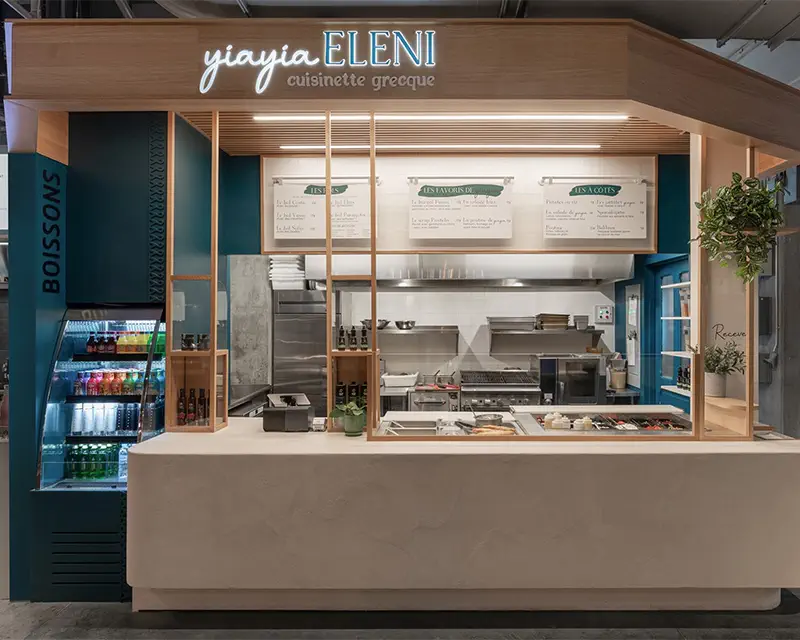 Blue and wood food kiosk with a stucco counter and illuminated sign