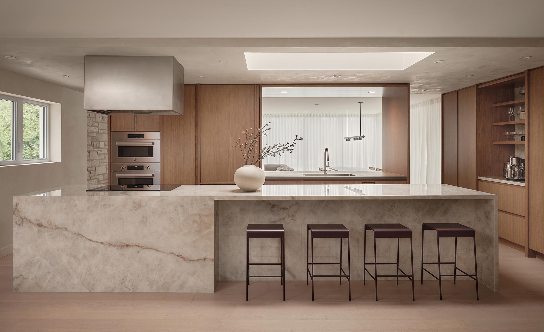 Kitchen with a veined marble island and a stainless steel suspended range hood, a residential interior design project in Saint-Bruno-de-Montarville by Entre Quatre Murs