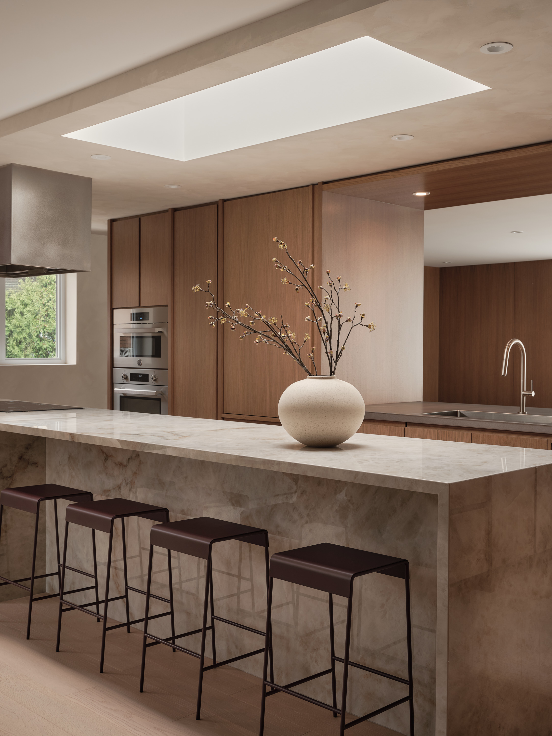 Marble kitchen island with a ceramic vase and flowering branches, wooden cabinets