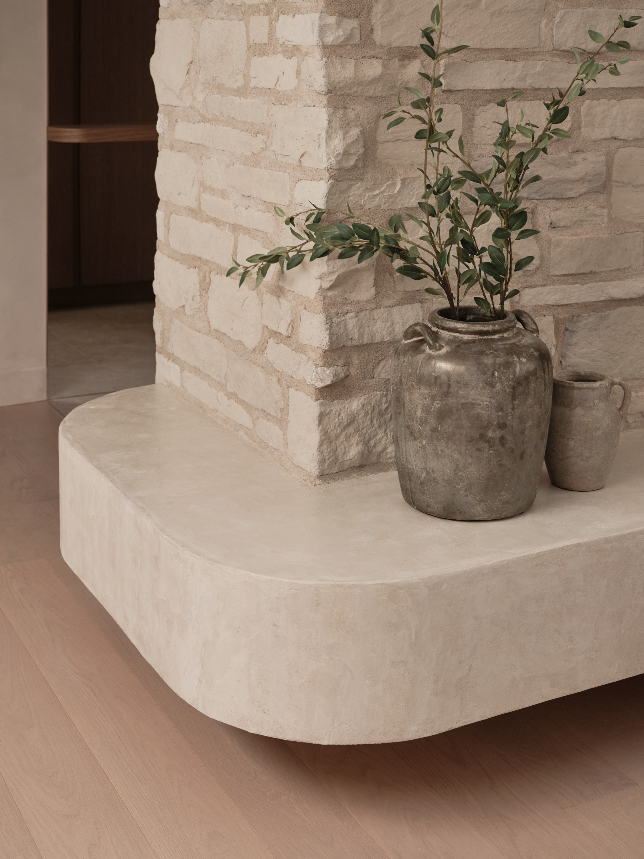 Natural stone niche with ceramic vases and an olive branch on a concrete bench