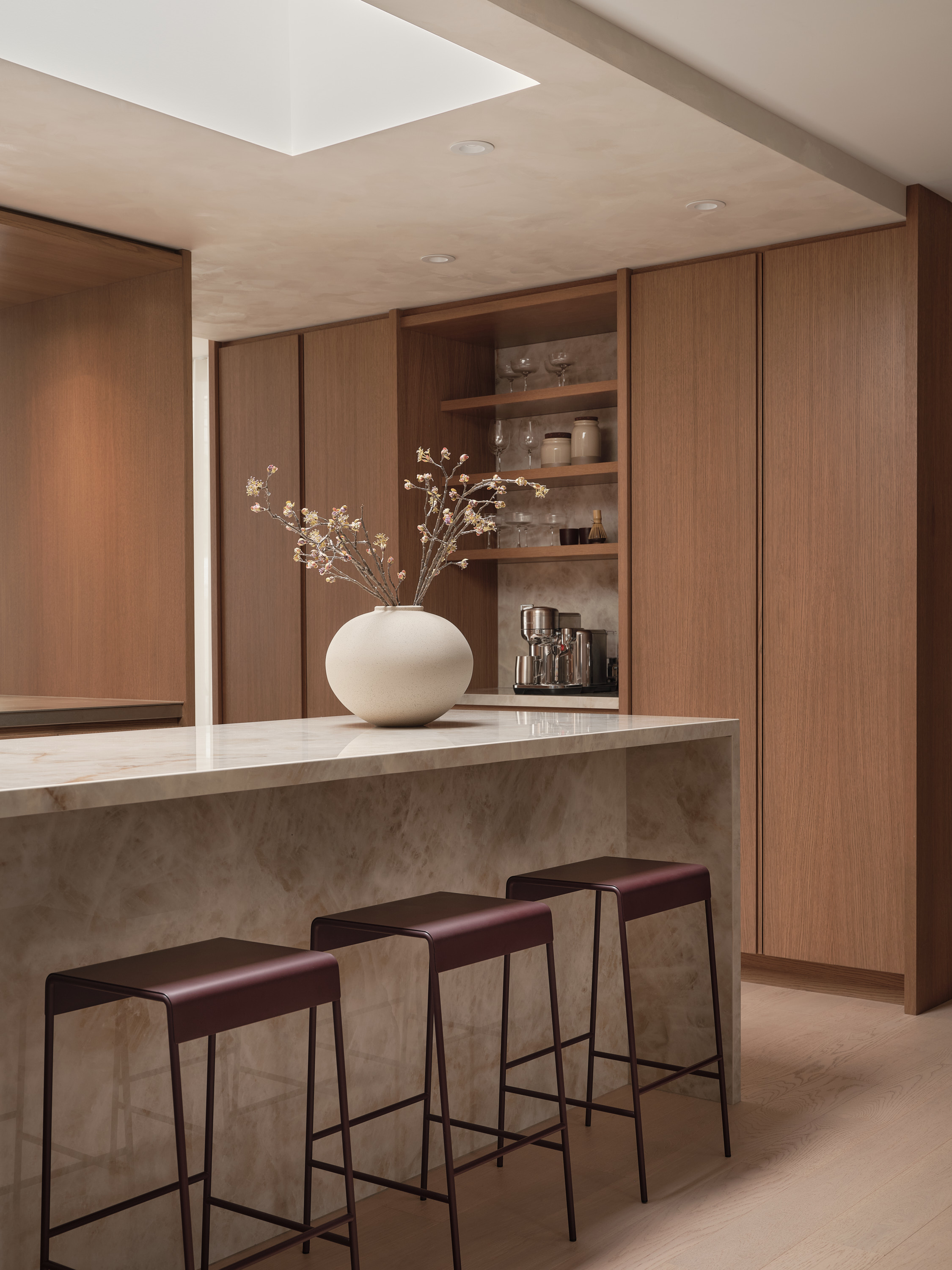 Pantry with wooden shelves, dishes, and a coffee maker; marble island in the foreground