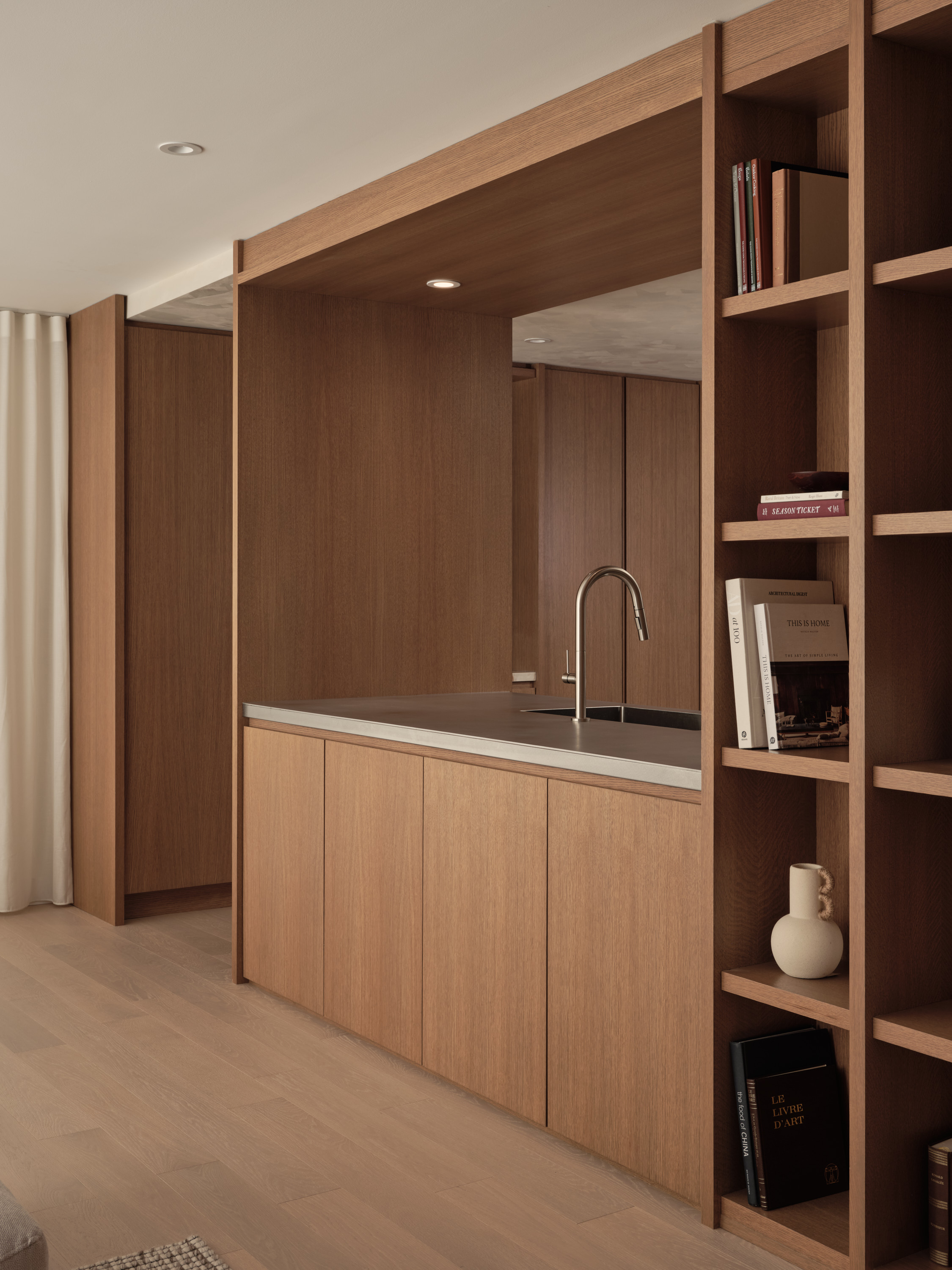 Bar with a sink, a wooden bookcase, and shelves lined with books and decorative items