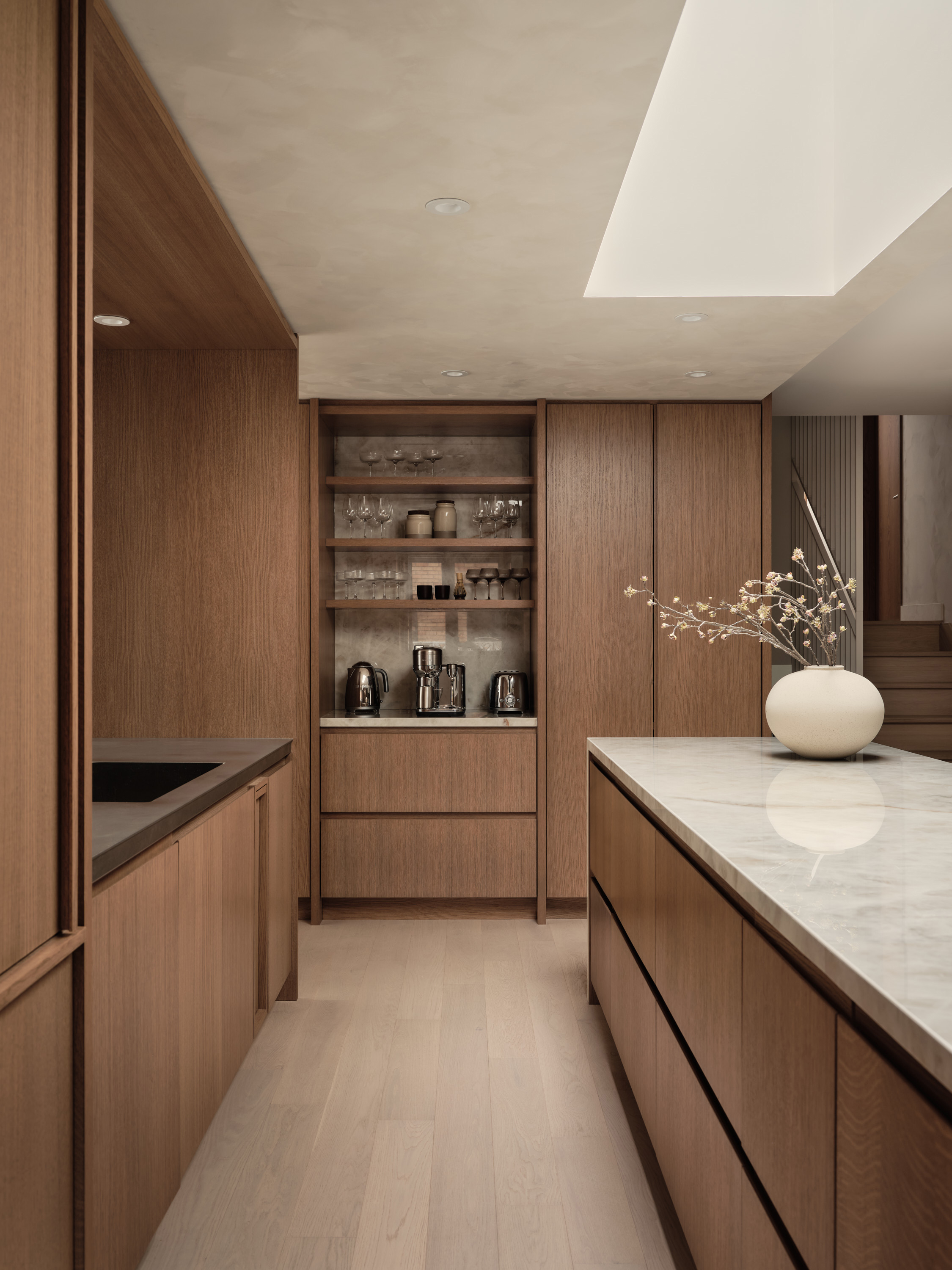 Pantry with wooden cabinets, glassware, and small appliances; marble kitchen island