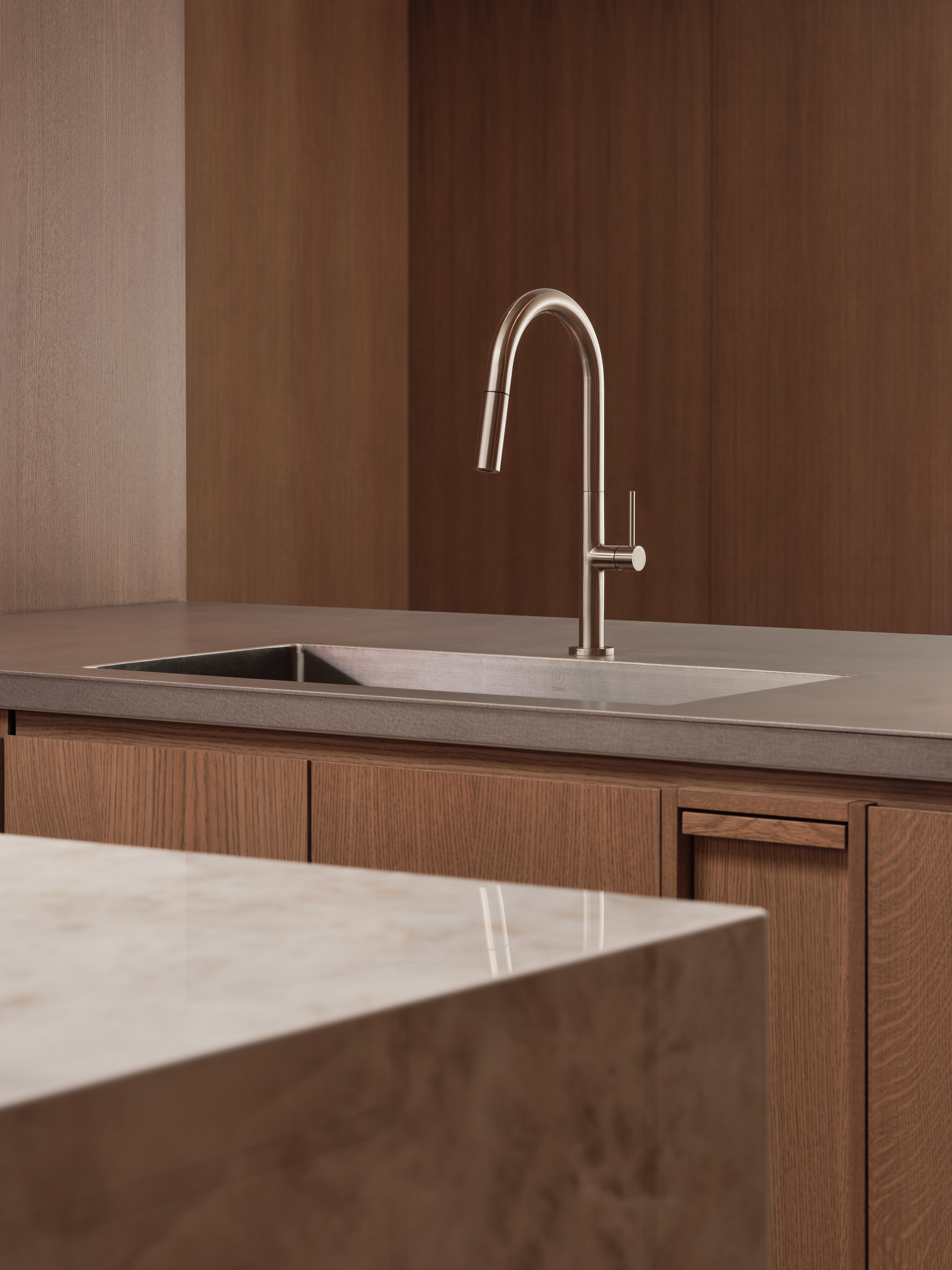 Stainless-steel kitchen faucet above a built-in sink, concrete countertop, and marble island