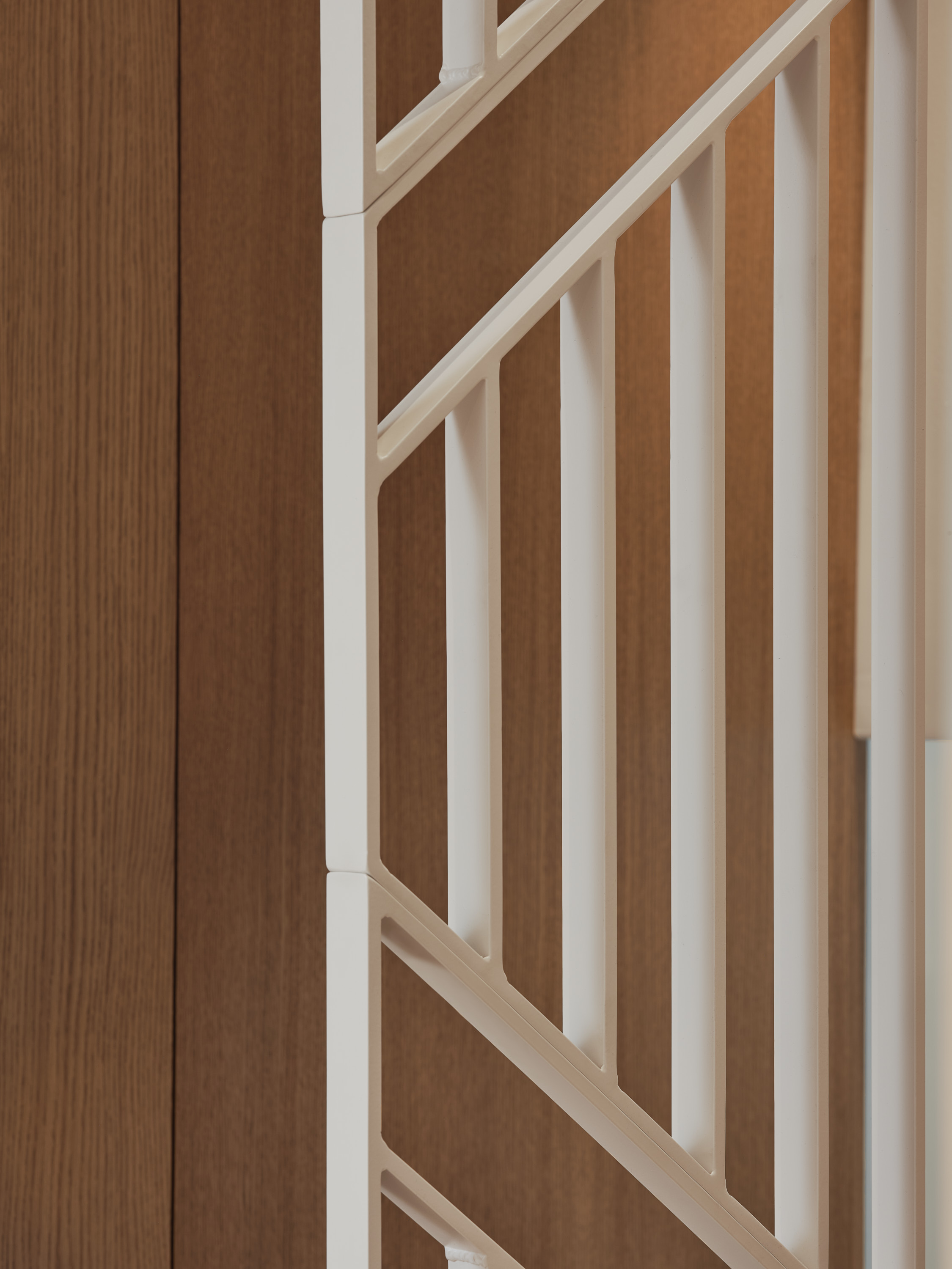 Close-up of the white, openwork stair railing against a backdrop of wood paneling