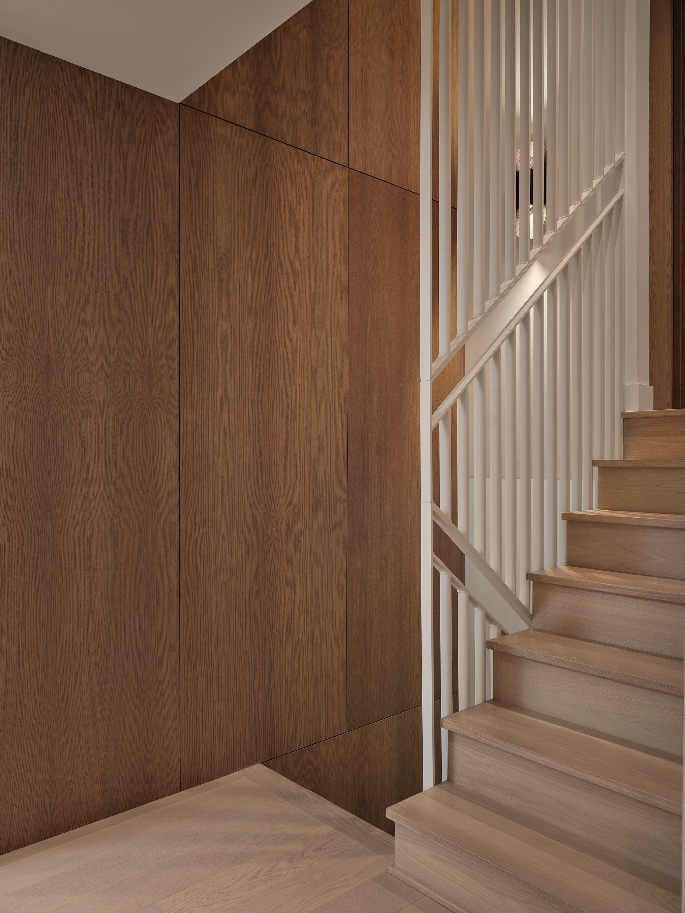 Wooden staircase with a white openwork railing and a wall made of wood paneling