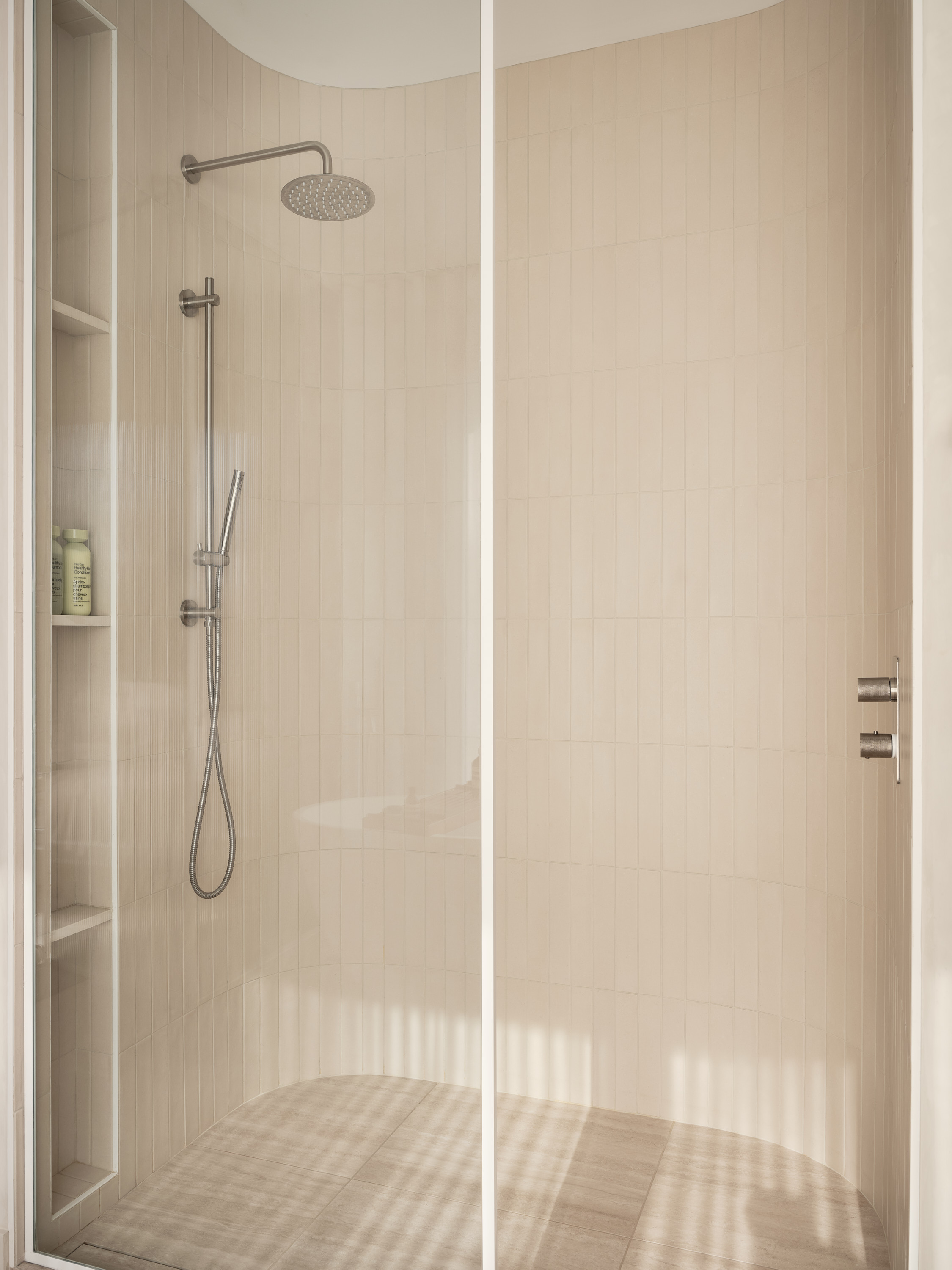 Glass shower with a rain showerhead and wall-mounted storage