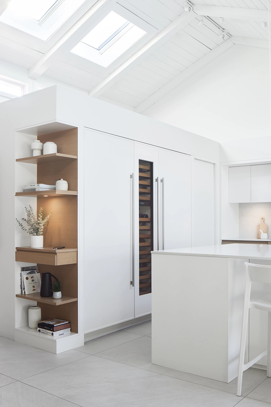 Pantry with a glass-fronted oak wine cabinet built into the white cabinets