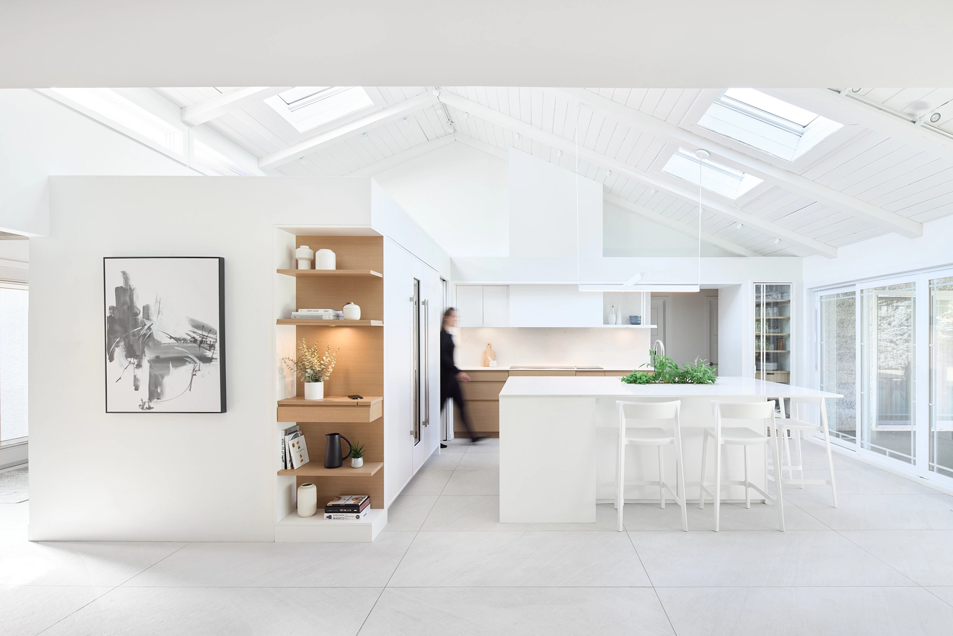 Open-concept kitchen with cathedral ceilings, a white central island, and a skylight; major renovation in Saint-Bruno by Entre Quatre Murs
