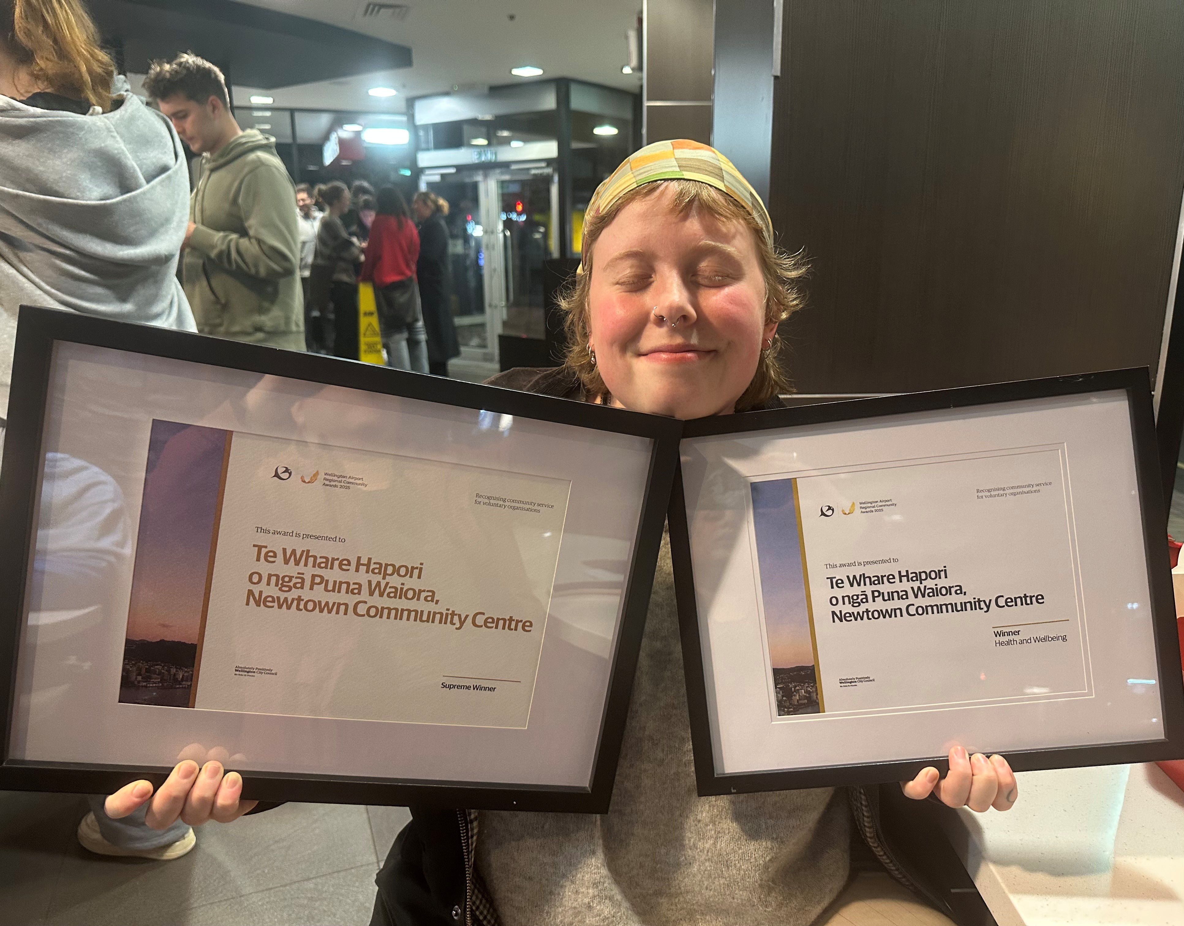 Charlie is smiling with two award plaques held up under her chin. 