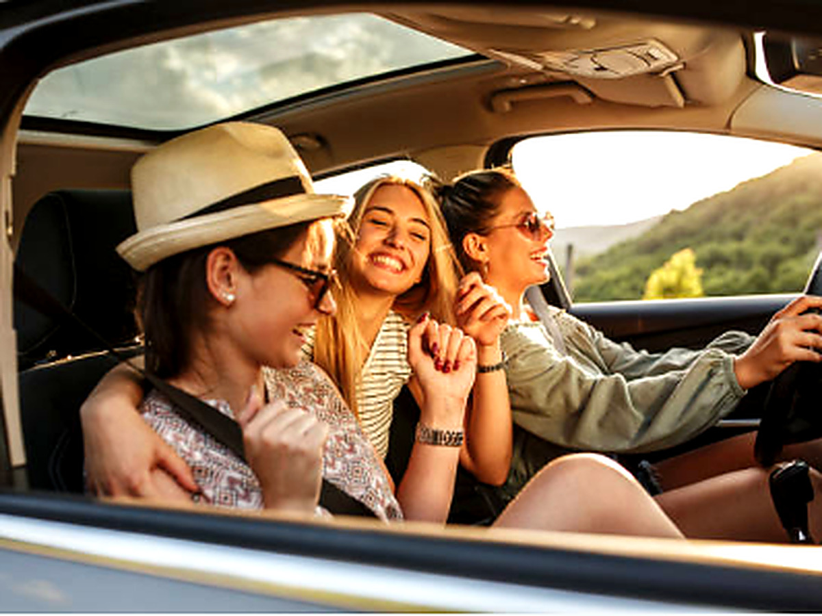 Trois amies souriantes en voiture pendant une escapade