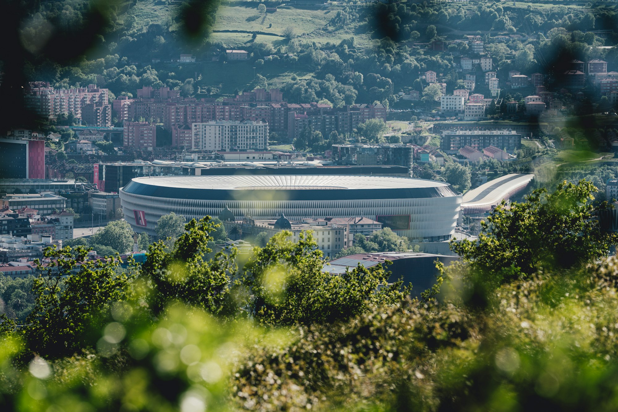 Le stade San Mamés de Bilbao vu depuis les hauteurs, au milieu des immeubles et des collines de la ville