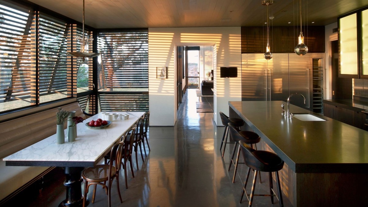 A kitchen with a long table and chairs and polished concrete floors