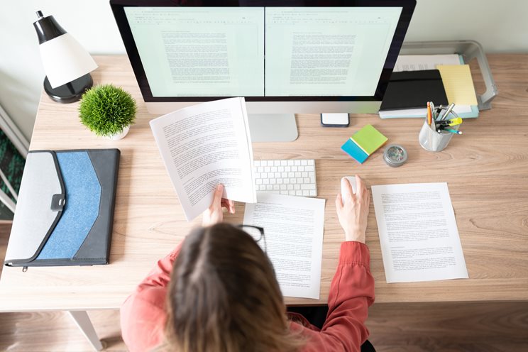 woman looking at paper and computer monitor