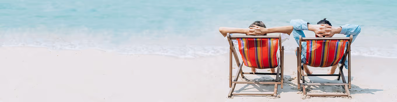 couple sitting in beach chairs staring out at water