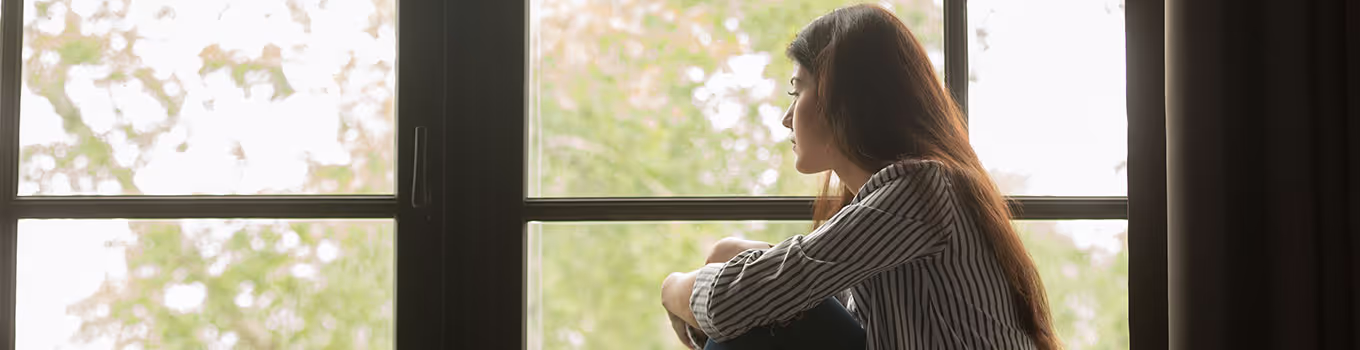 depressed, anxious, young woman staring out window