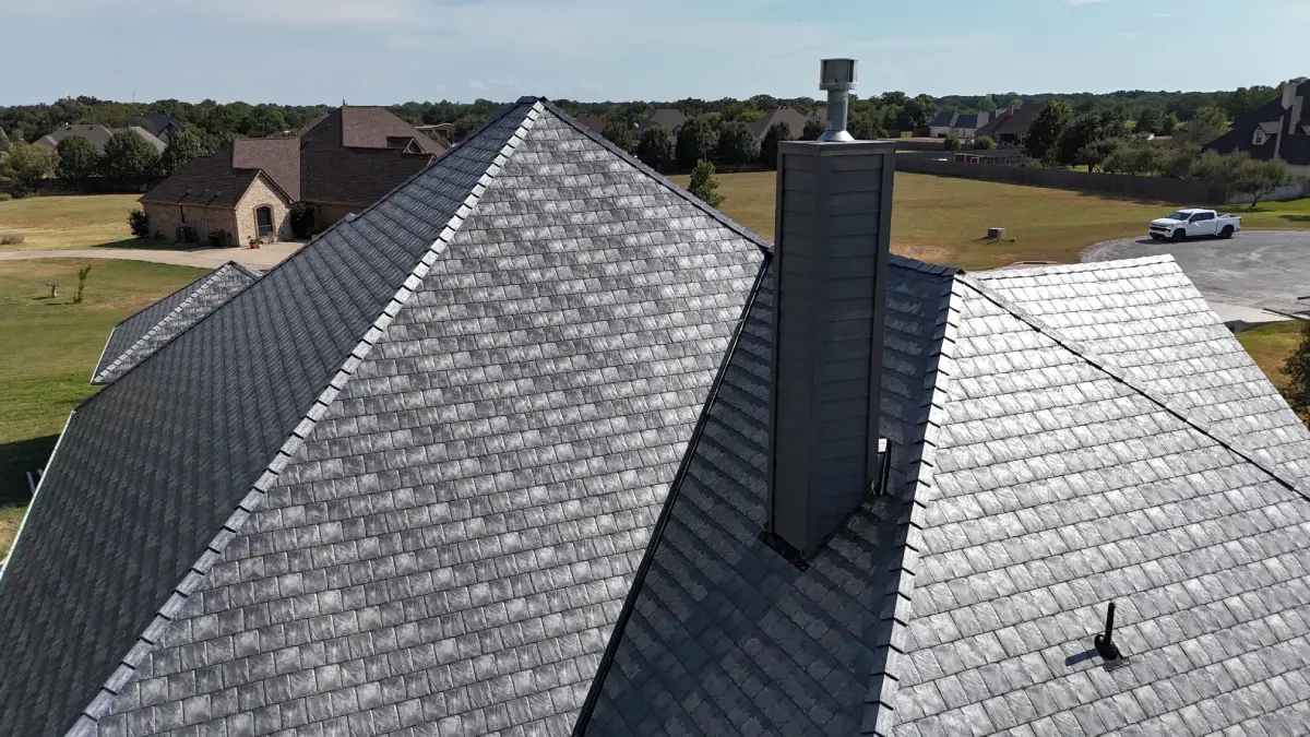 Euroshield roof on a house with a chimney and a suburban neighborhood in the background.