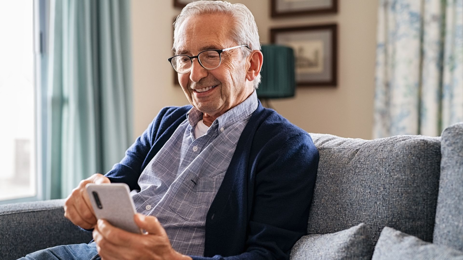 A senior man uses his favorite app on his mobile phone.
