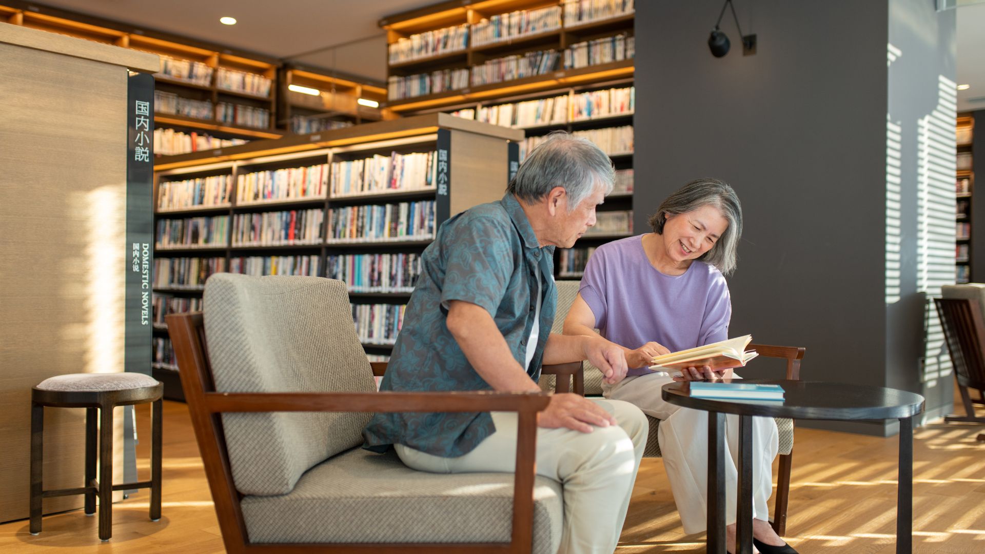 Two seniors practice a new language together while sitting in a library.
