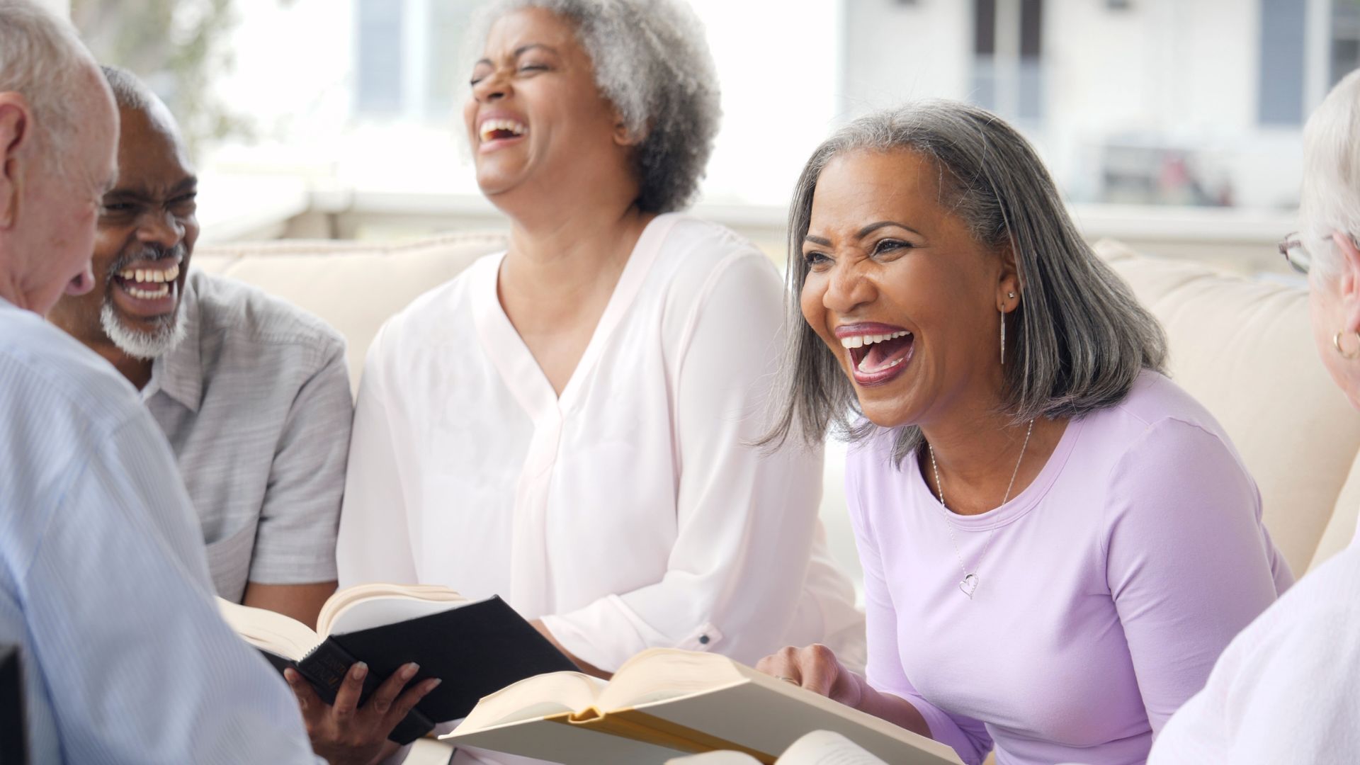 A group of seniors laughs in an independent living community.